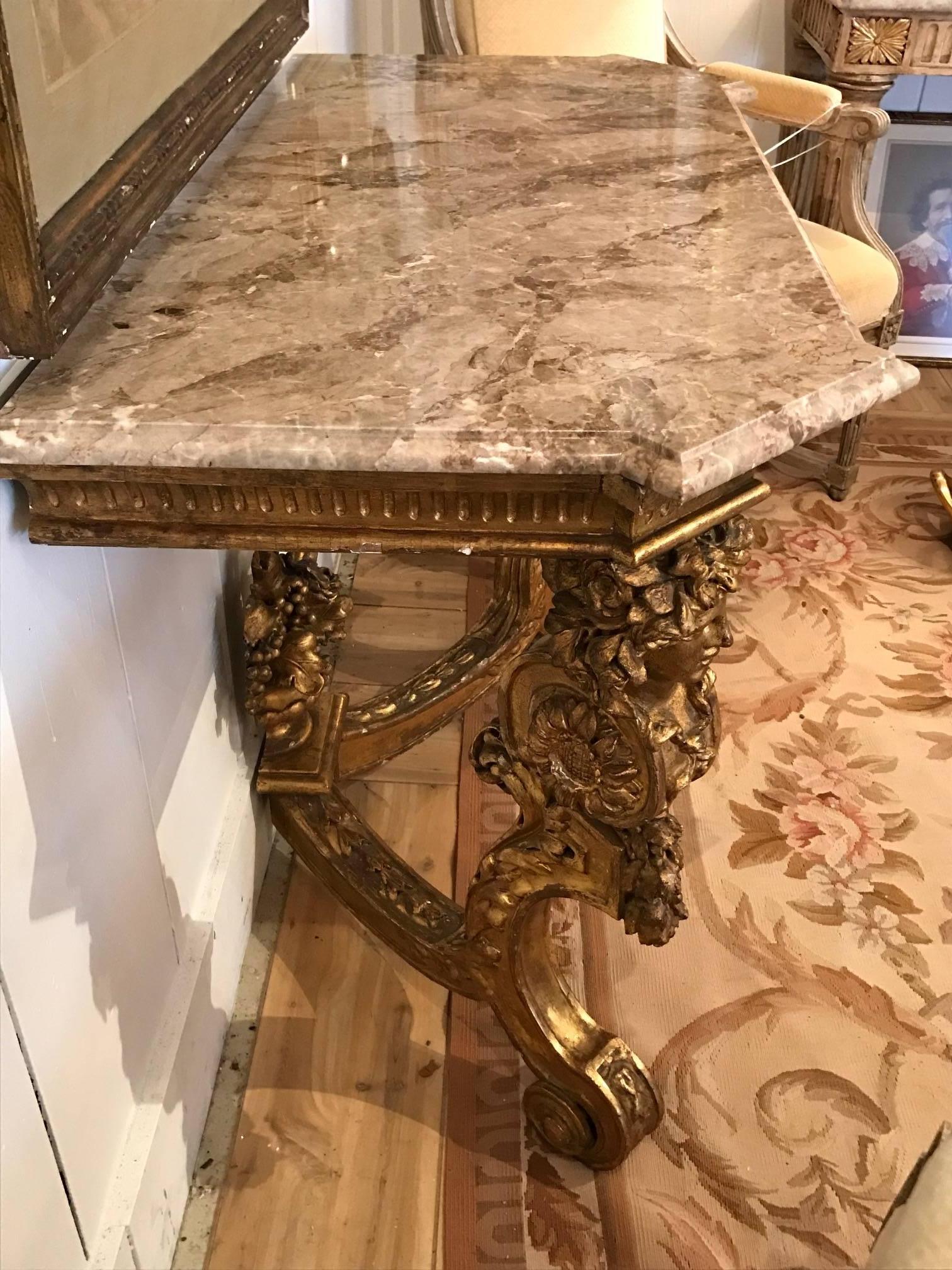 Very elegant console table having ornate carved giltwood base with two figural legs and a pretty flower basket central finial, topped with a lovely etched and bevelled marble top with lively neutral colored veining.