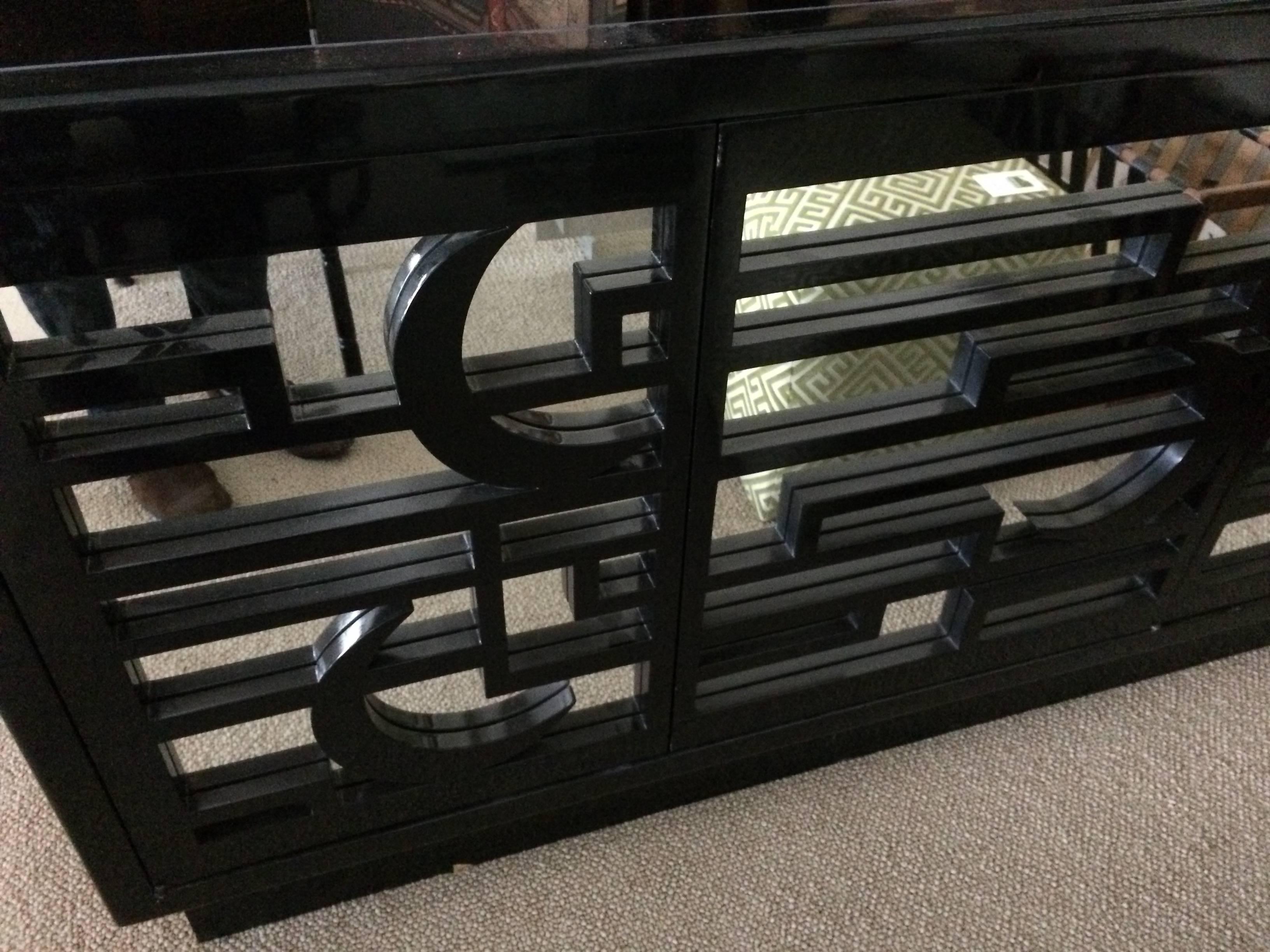 Fabulous black lacquer and mirrored credenza or sideboard. The front three doors and side panels have recessed mirror and black geometric fretwork. Black glass top is inset. Lots of storage inside including adjustable shelves and some drawers.