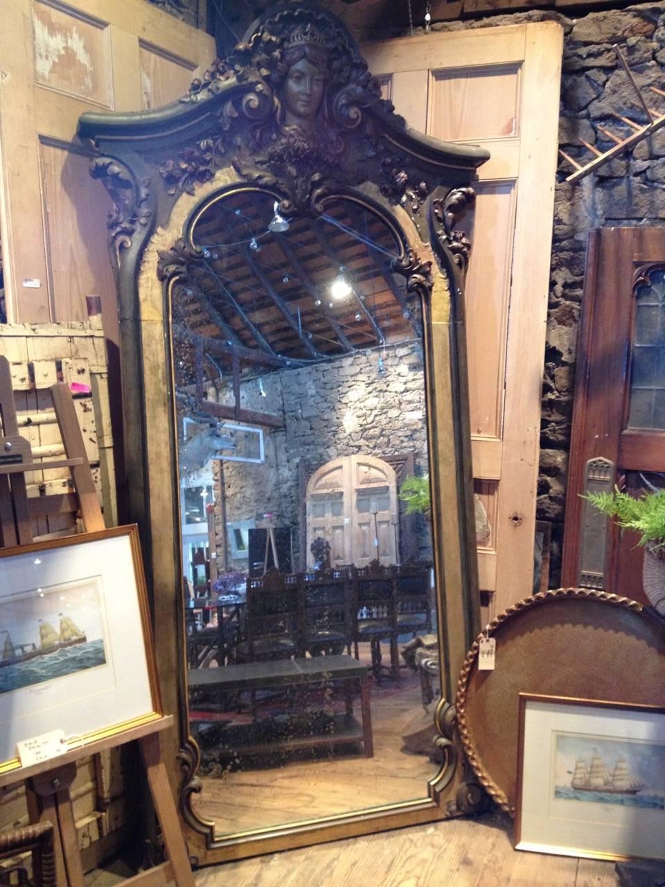 Monumental carved Italian mirror, circa 1900. Gesso over wood with original mirror. Has a gilt border with muted paint colors in bluish green with gold and brown highlights. Weighs approximately 300 lbs. 3 inches deep except for the top which is 8