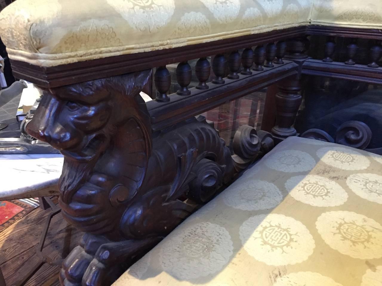 Pair of American Victorian mahogany corner chairs, circa 1890, that when pushed together make a handsome settee. Carved wood is impressive with animal figures and turned spindles that make a gallery near the top periphery.