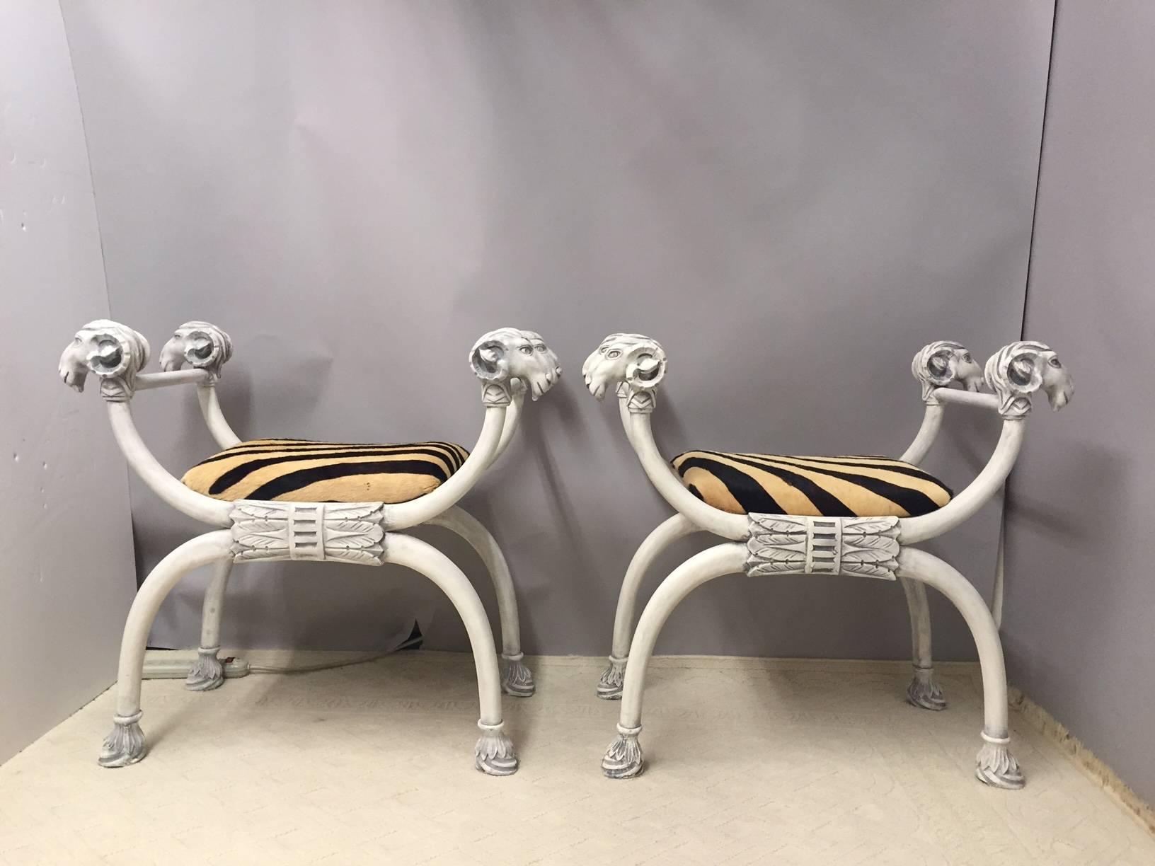 Amazingly theatrical pair of Italian benches having hand painted French matte grey white frames with fabulous sculptural ram's heads and carved leaf motife feet, finished with upholstered seats in zebra patterned cowhide.
 