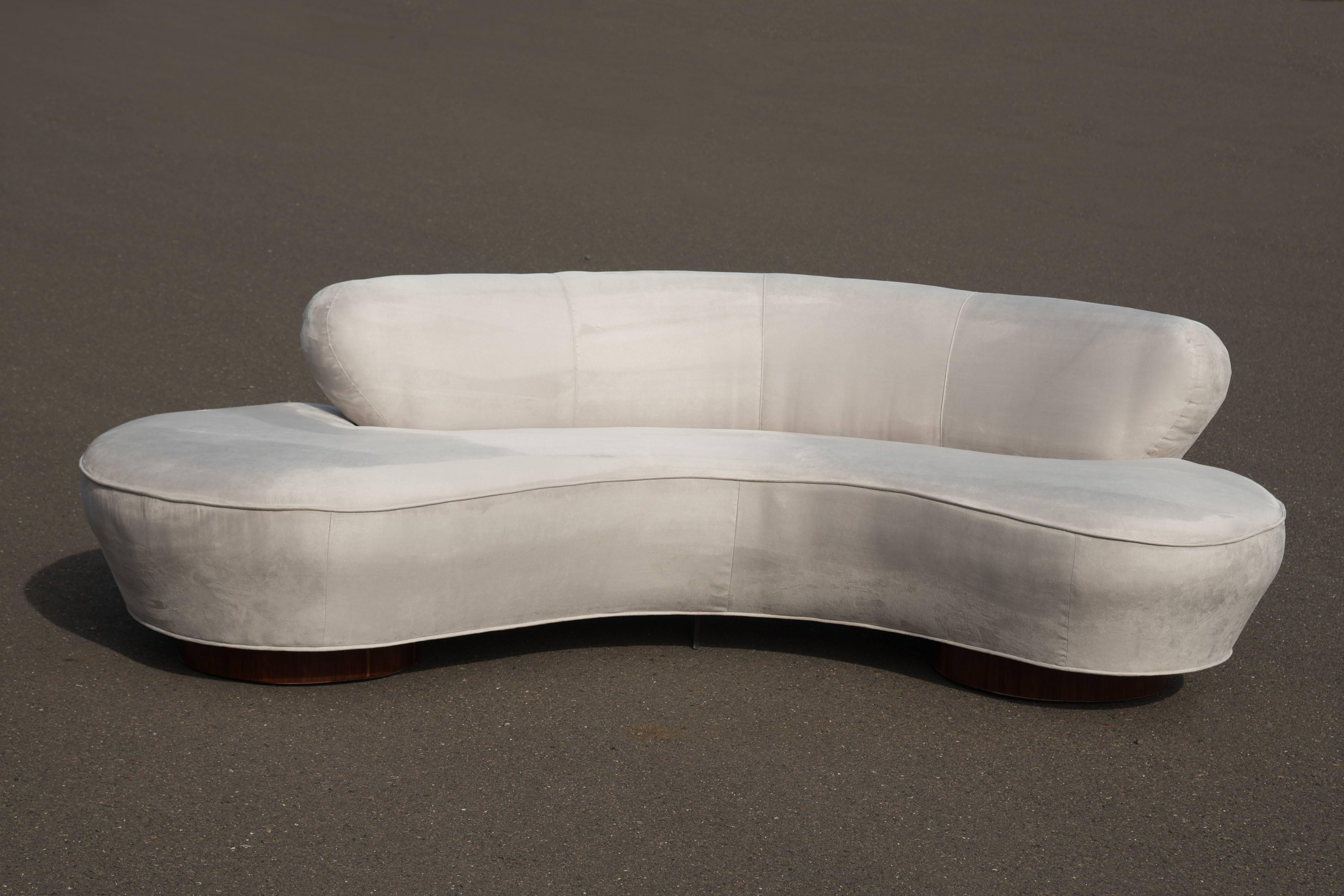 A glamorous Vladimir Kagan for Directional Serpentine or Cloud sofa. Newly recovered in an elegant very light gray/ silver ultra suede.   The original fabric covered bases have been upgraded to rosewood.  Directional tag.
Fabric swatches available