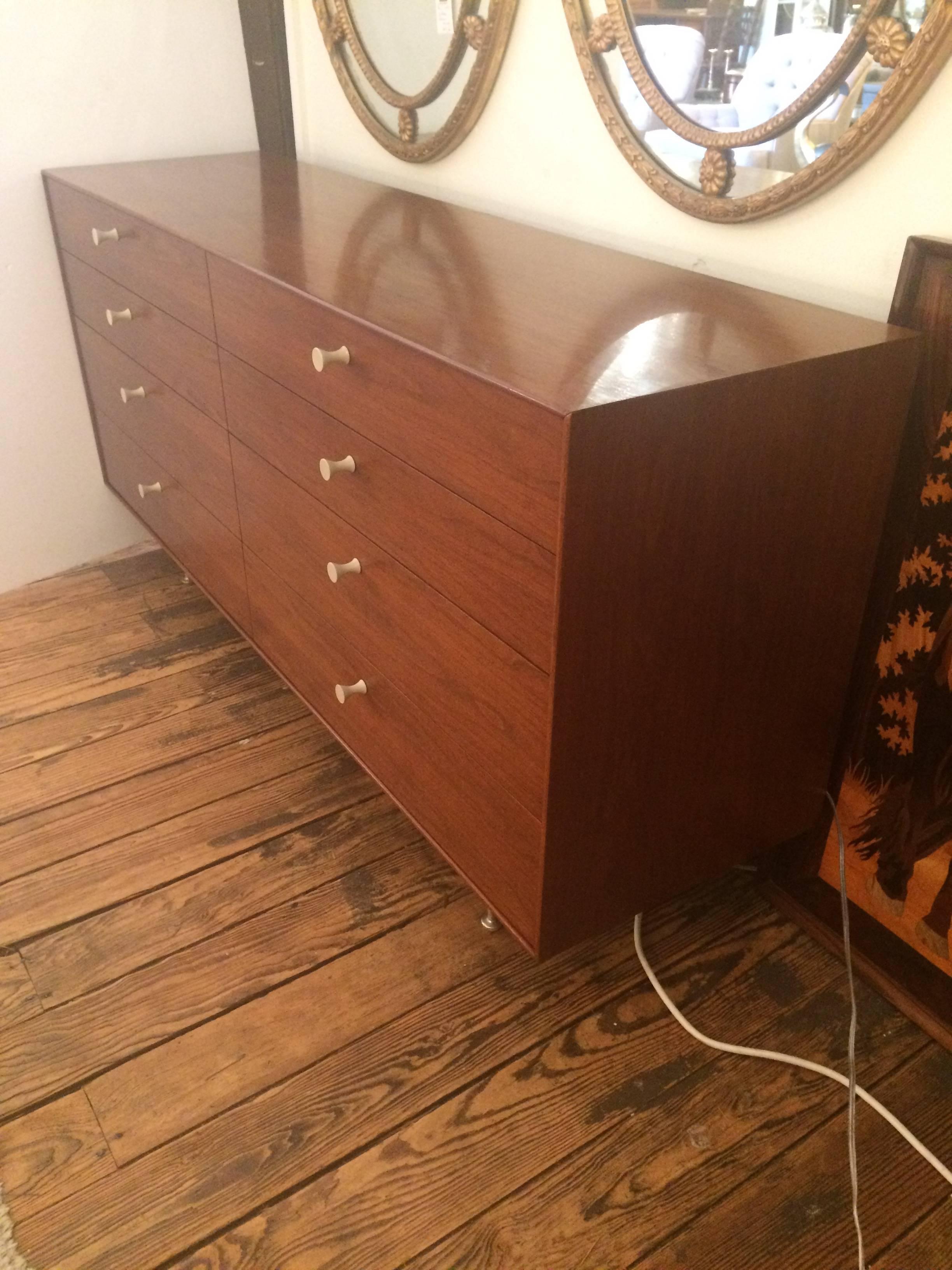 Superb sleek Mid-Century Modern design by the iconic George Nelson for Herman Miller, thin edge walnut veneer very large eight-drawer dresser with tapered aluminium legs and classy white hour-glass shaped hardware.