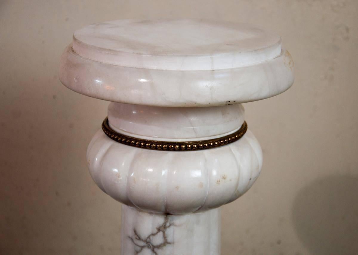 This French vintage marble pedestal is carved in white marble with soft grey
veins. It features bronze banding at the top, in the middle, and on the
bottom and stands on small bronze feet.
Dimensions of marble pedestal are: 9.5 x 9.5 x 37.5