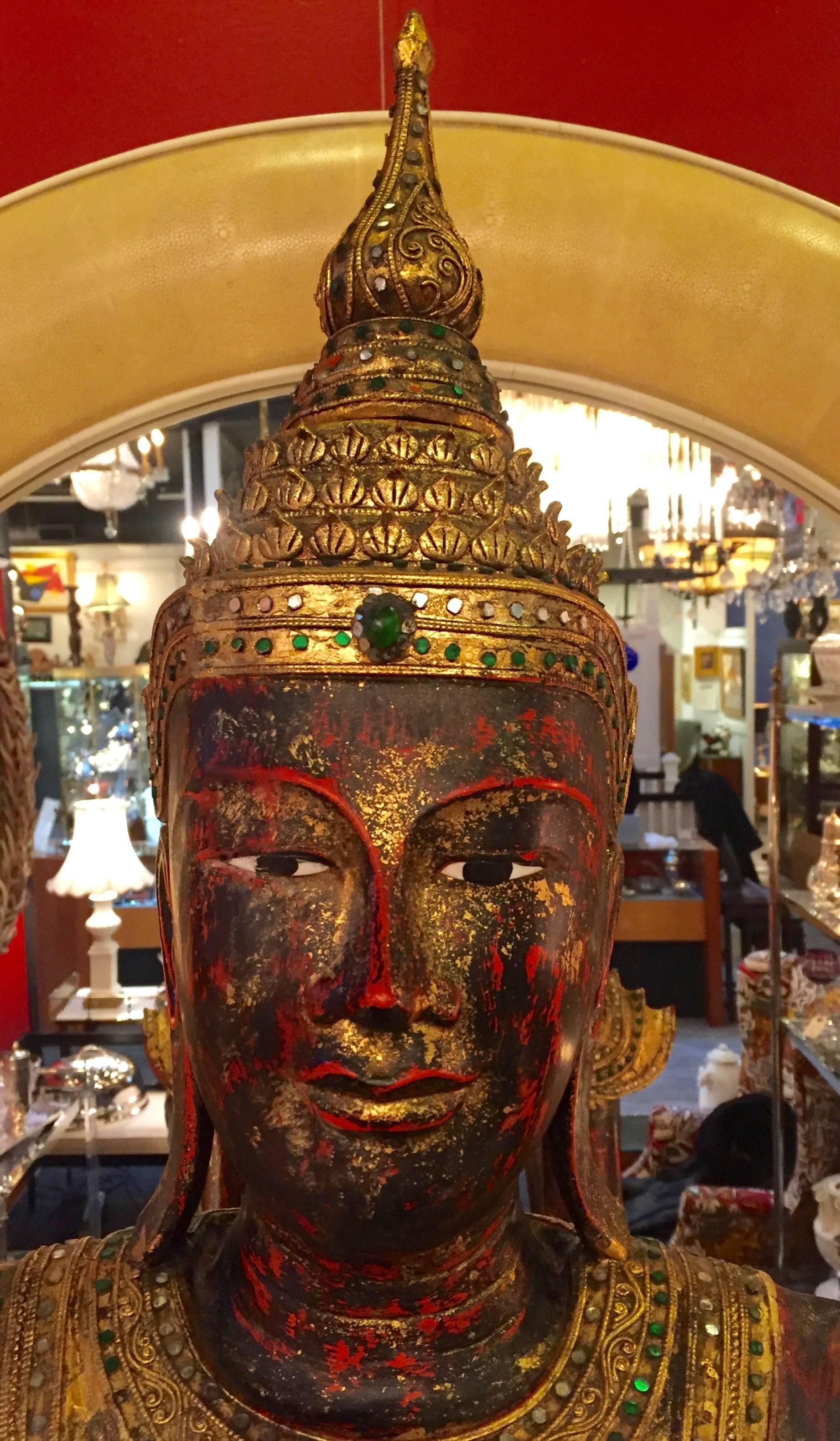Lifesize 6 ft tall burnished gold Thai Buddha with red underpaint and meticulous colored cut-glass jewels adorning the robe and head dress. Very impressive.