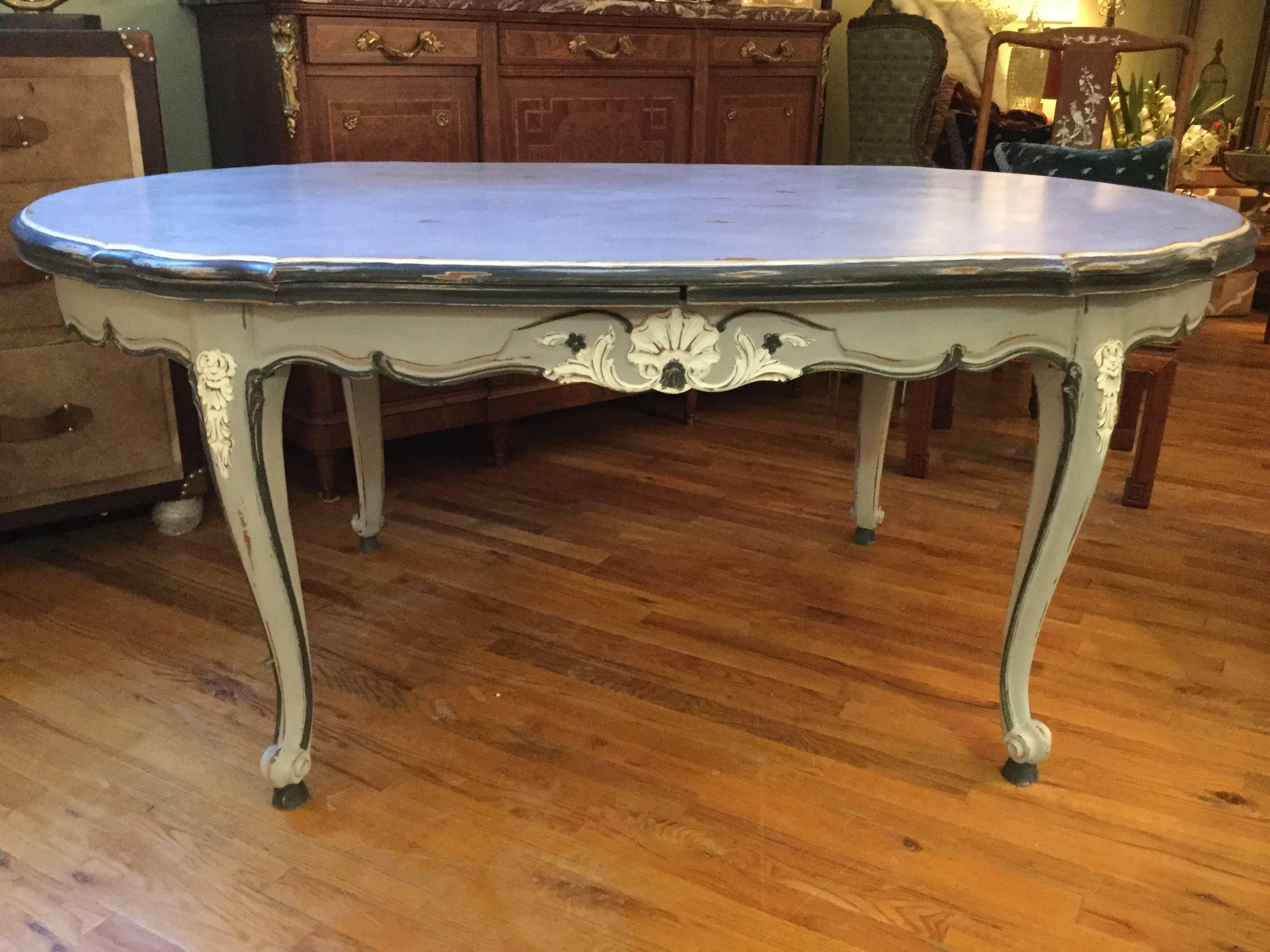 Louis XV-style cherry oval dining table, circa 1930s. With large leaves
stored right under the top, this refectory table has been painted in shades
of light and dark grey with white accents on the carvings around the apron
and on the legs. When