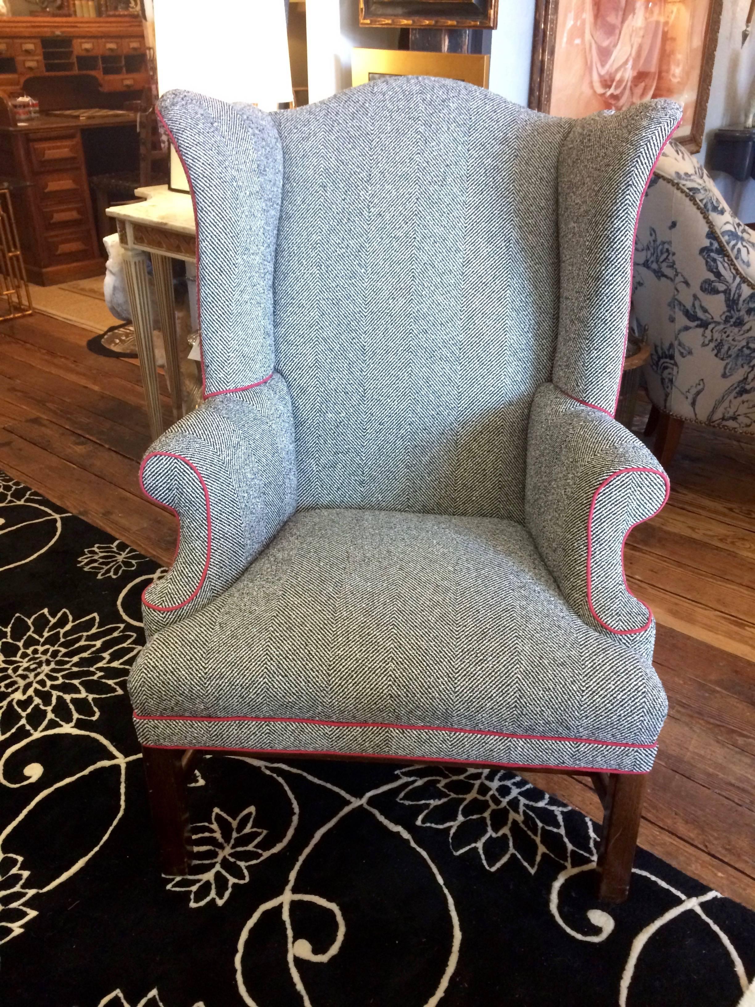 Handsome wing chair in new black and white herringbone fabric trimmed with a contrasting red welt. The fabric gives the appearance of men's suit fabric. Chair has a straight mahogany leg. 

Measures: Seat depth 20”.