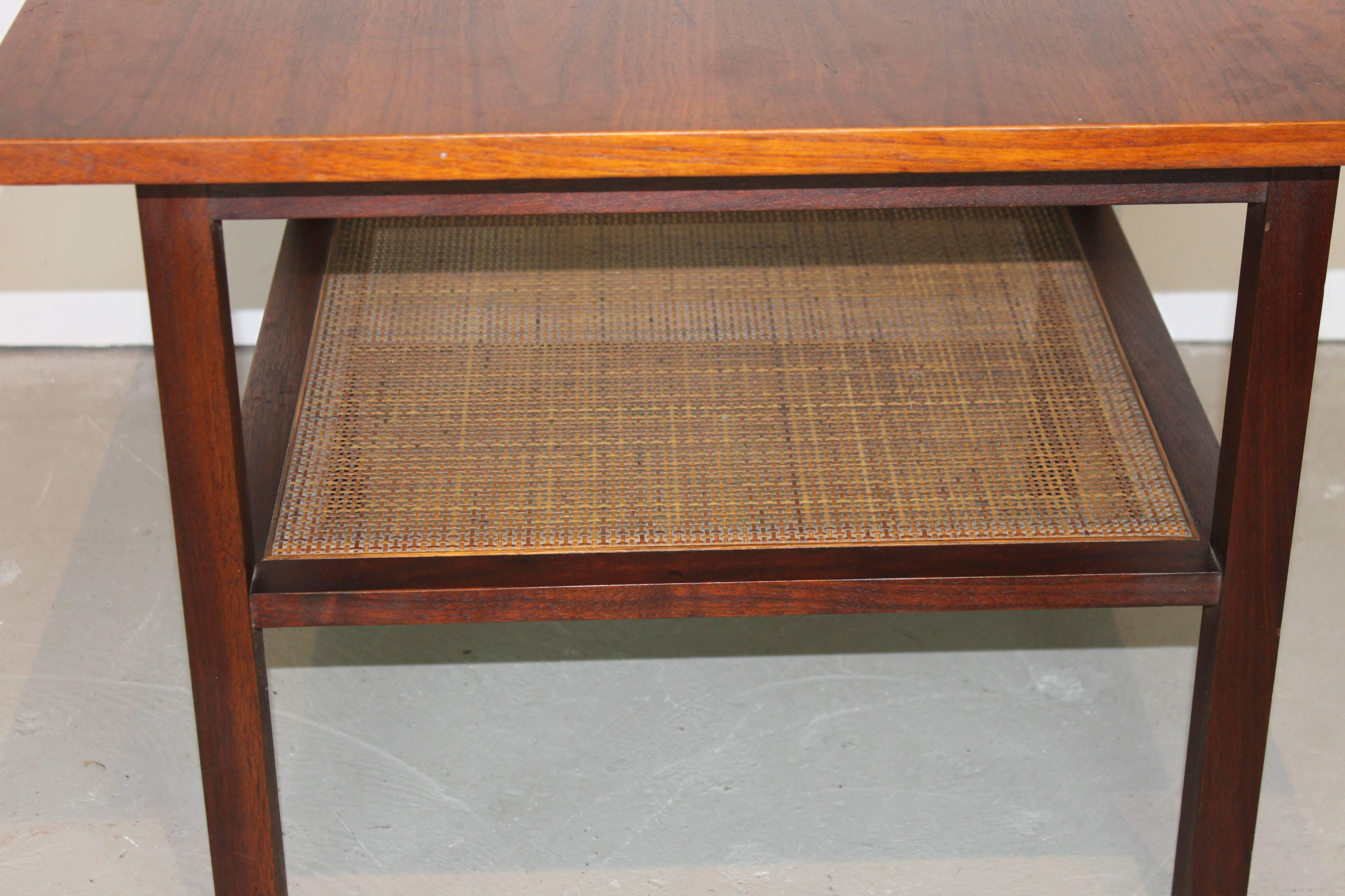 Pair of Mid-Century Modern walnut top and rosewood base end tables with cane shelf. Tables are in very good original condition. Random spots on finish noted on the tabletops. Overall in very good shape. One minor unnoticeable nick to the cane shelf