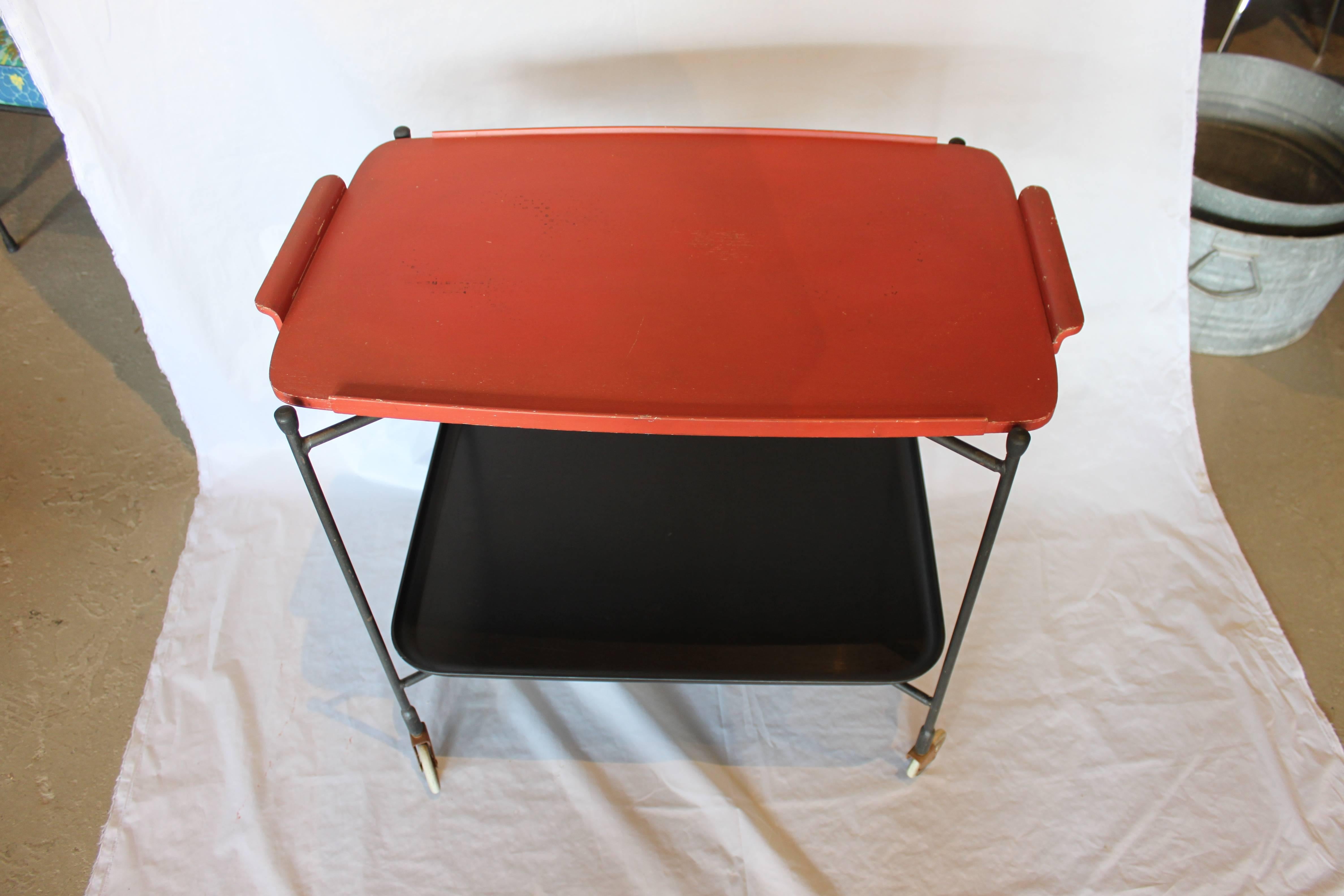 Beautiful tea or bar cart with two removable trays. Asian Inspired color combination. Red painted wood tray with minor paint loss due to age. Vintage grainware matte black acrylic tray is in mint condition. The foldable iron frame is in great shape.