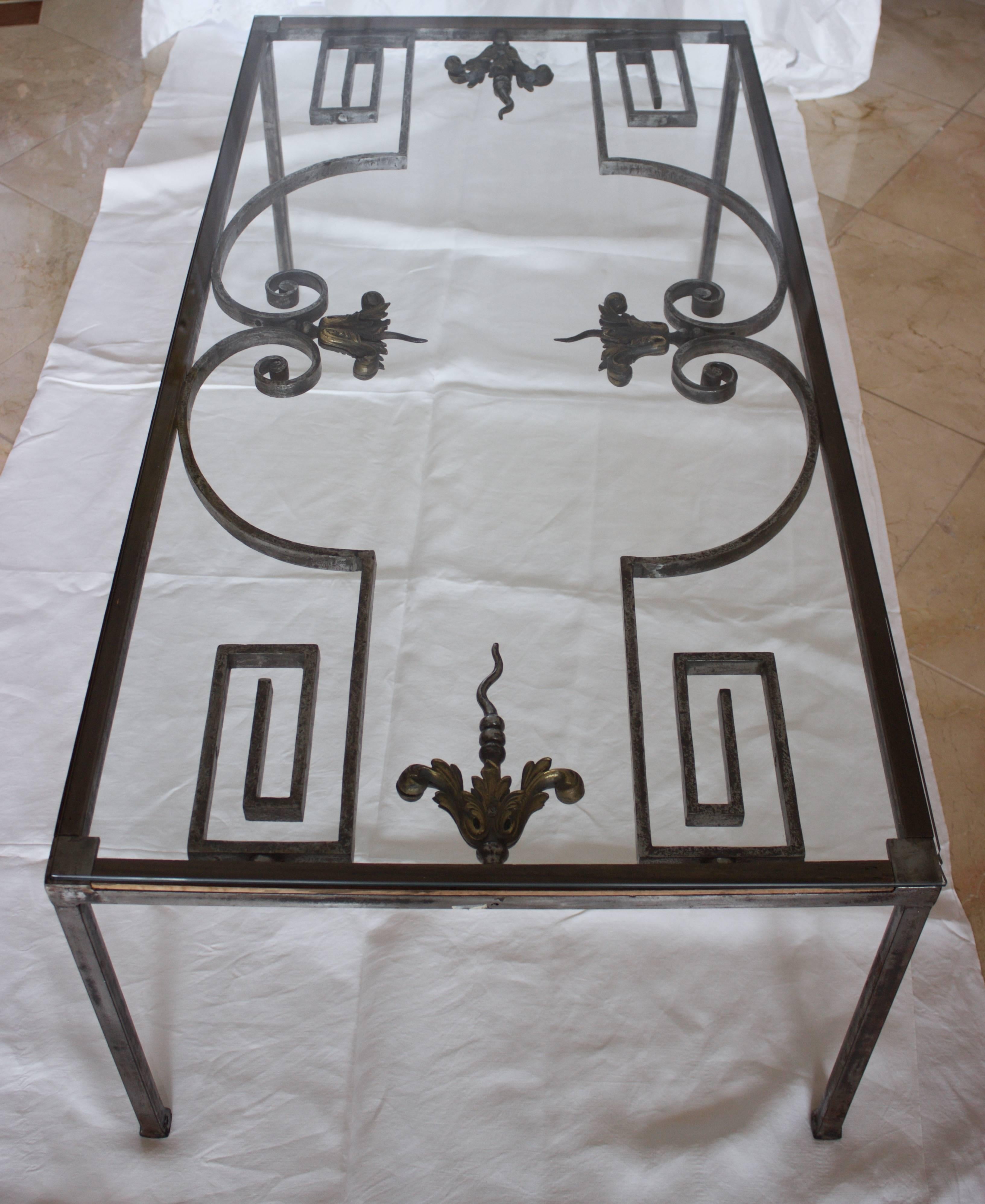 Outstanding table made of hand forged steel and cast bronzes from a 19th century French gate. The legs in forged steel as well were a later addition skillfully done. Fully covered by a glass panel -.25