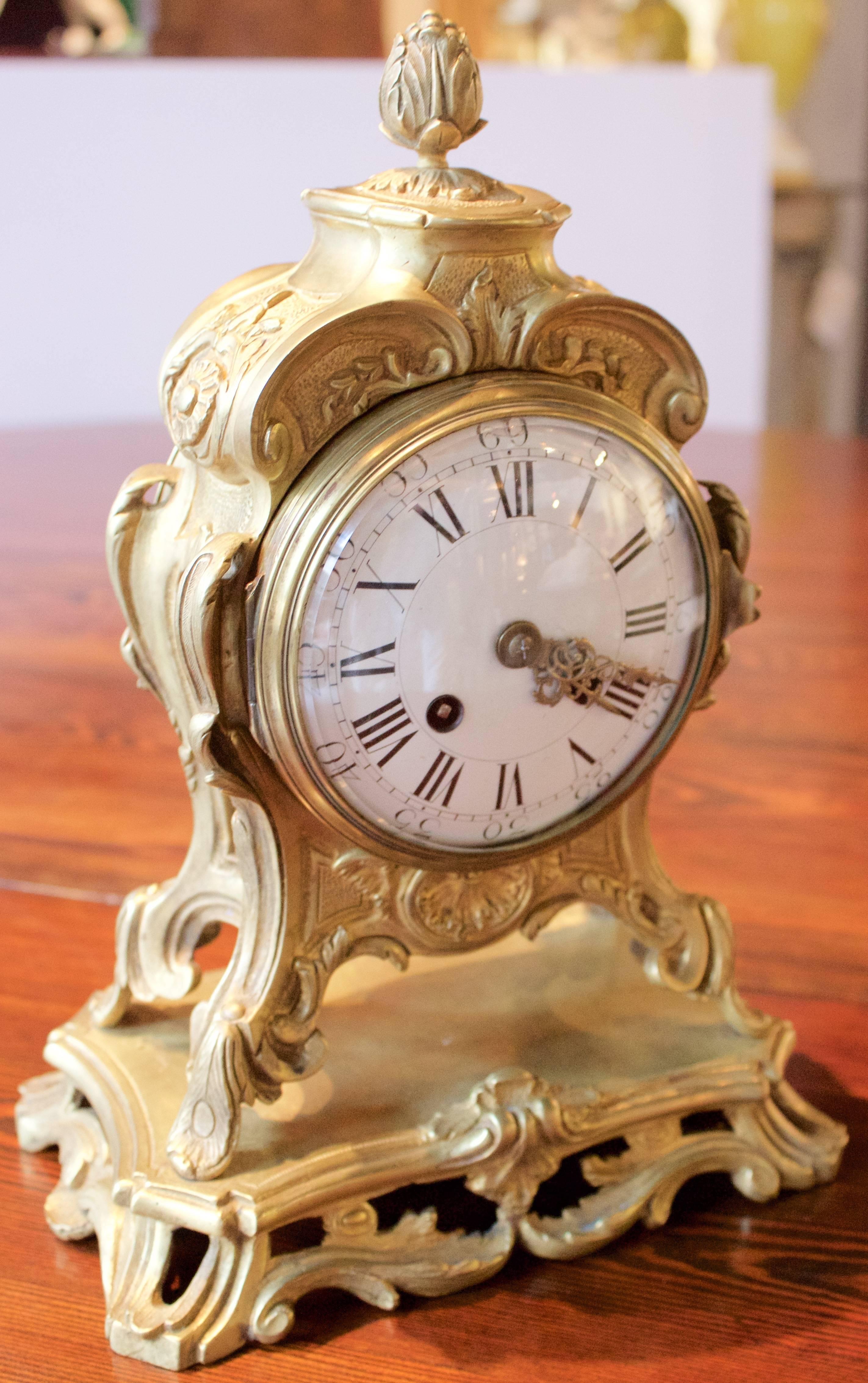 Handsome mantel clock with gilded bronze in Rocaille style adorned by acanthus leaves and topped by a fruit. \White glazed copper dial with black painted Roman and Arabic numerals. Hands in casted bronze. Movement made by 