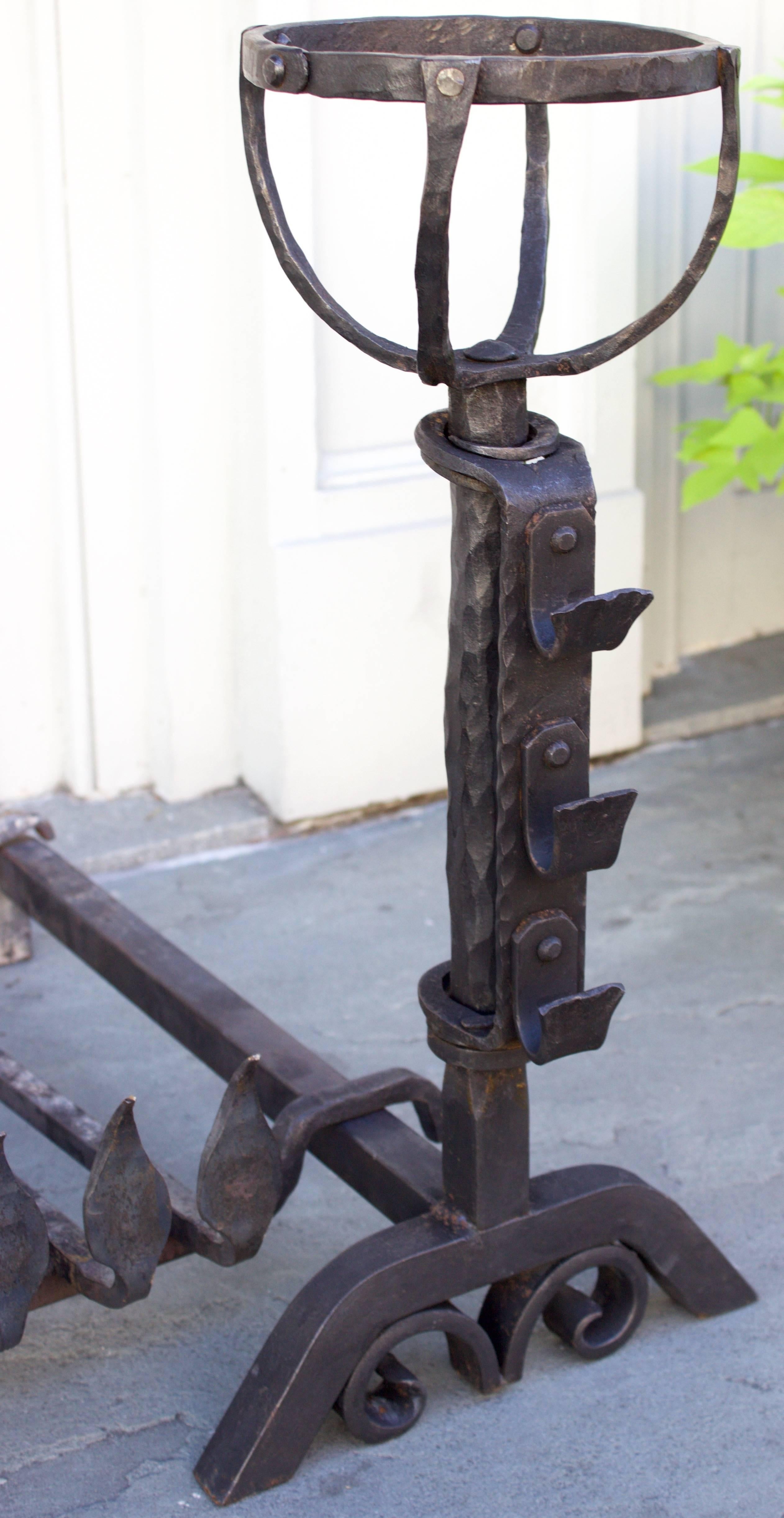 Landier is the French name for this kind of andirons. They are high hand-forged iron posts with spit hooks for rotisserie and at top a skeleton receptacle to support soup or other pots to be warmed. It comes with its original grate, which is rare.