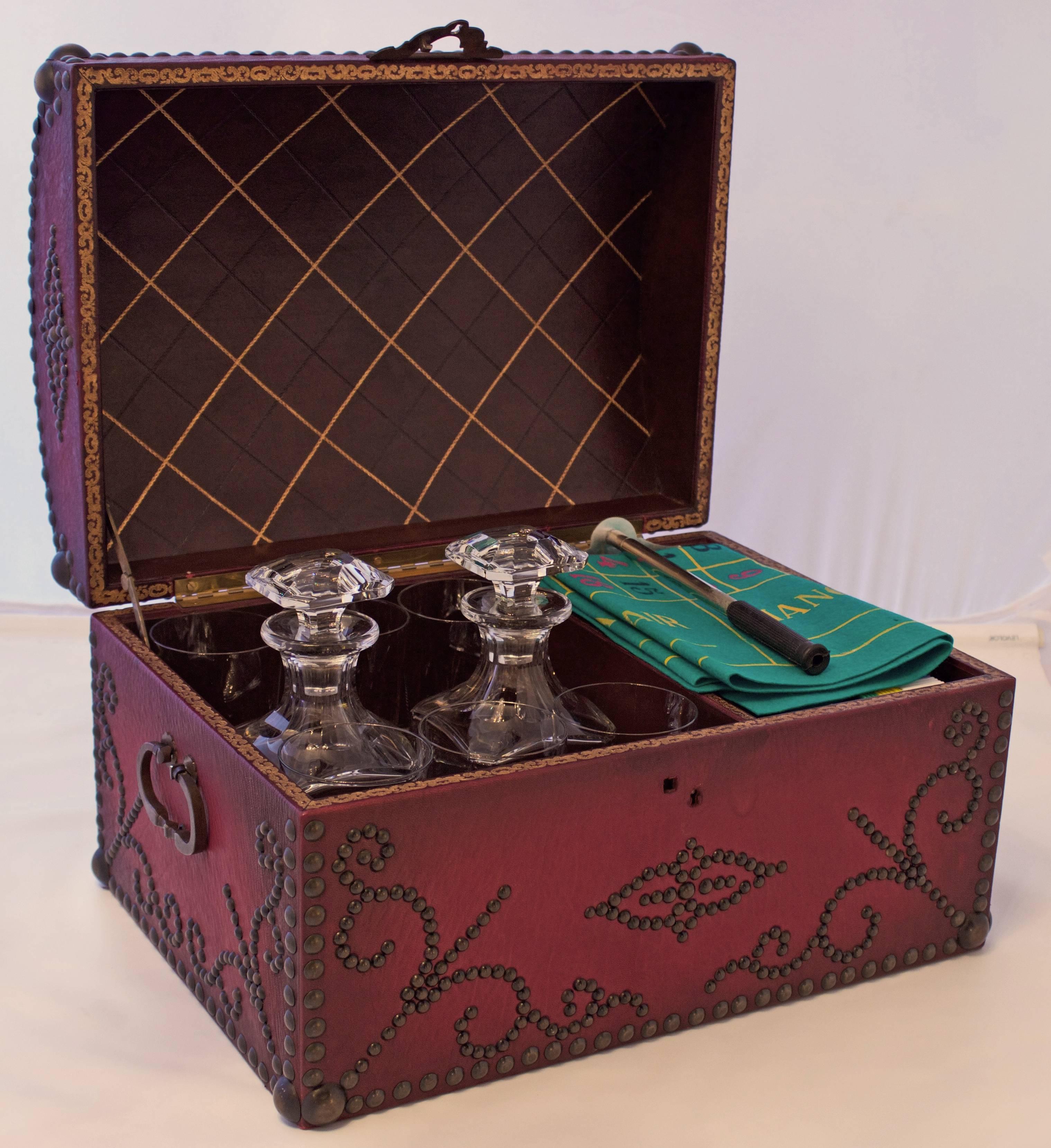 Extremely rare Art Deco travel case with two bronze handles and Burgundy colored leather ornamented with nails in the 18th century manner. Its opening reveals 12 pieces of Baccarat crystal: Two squared whisky decanters, six large (H6