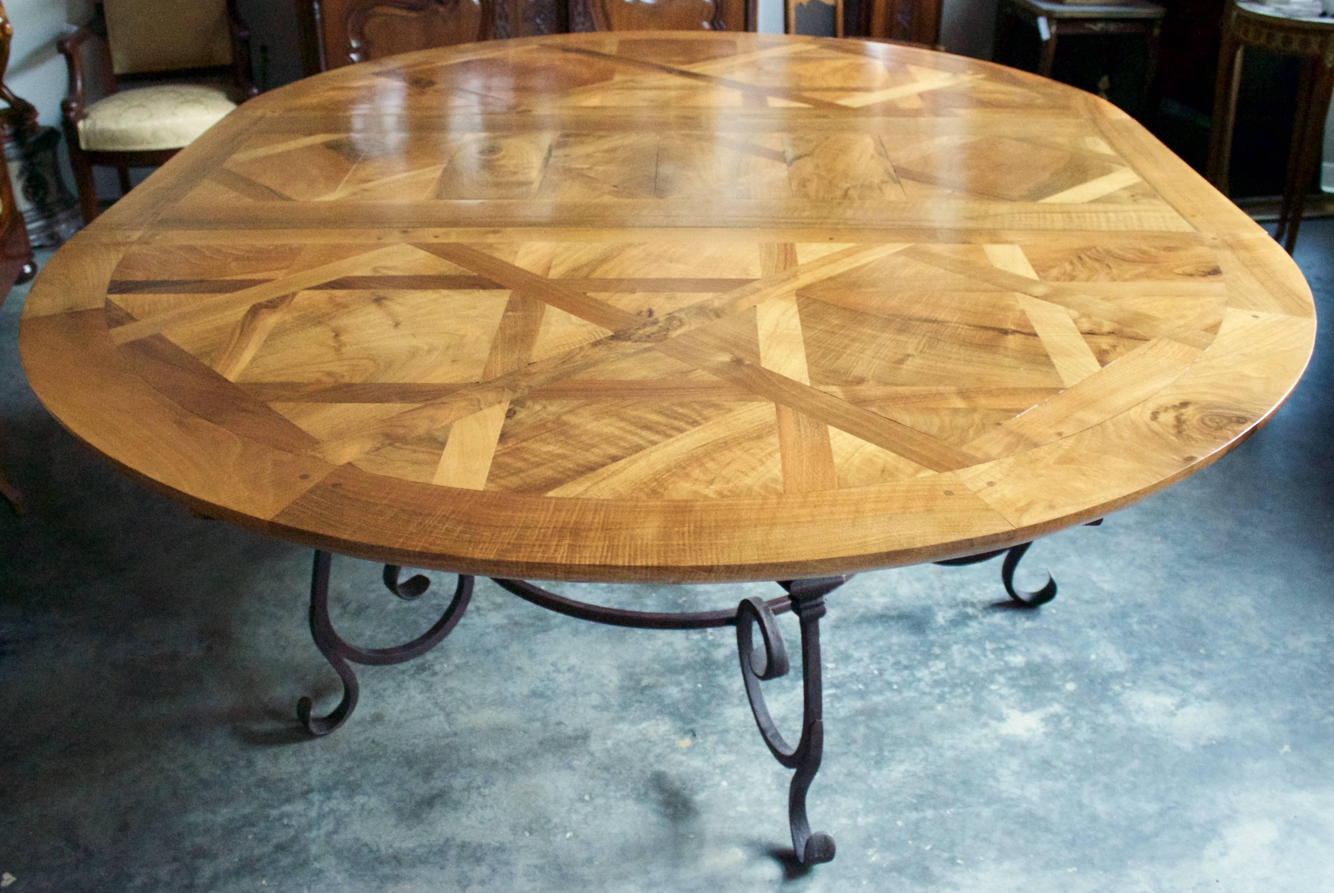 Gorgeous parquet top table that can be used round or oval due to a single central leaf. Can seat -when  oval- 12 to 14 people.Made of French walnut top resting on a beautifully scrolled wrought iron base.