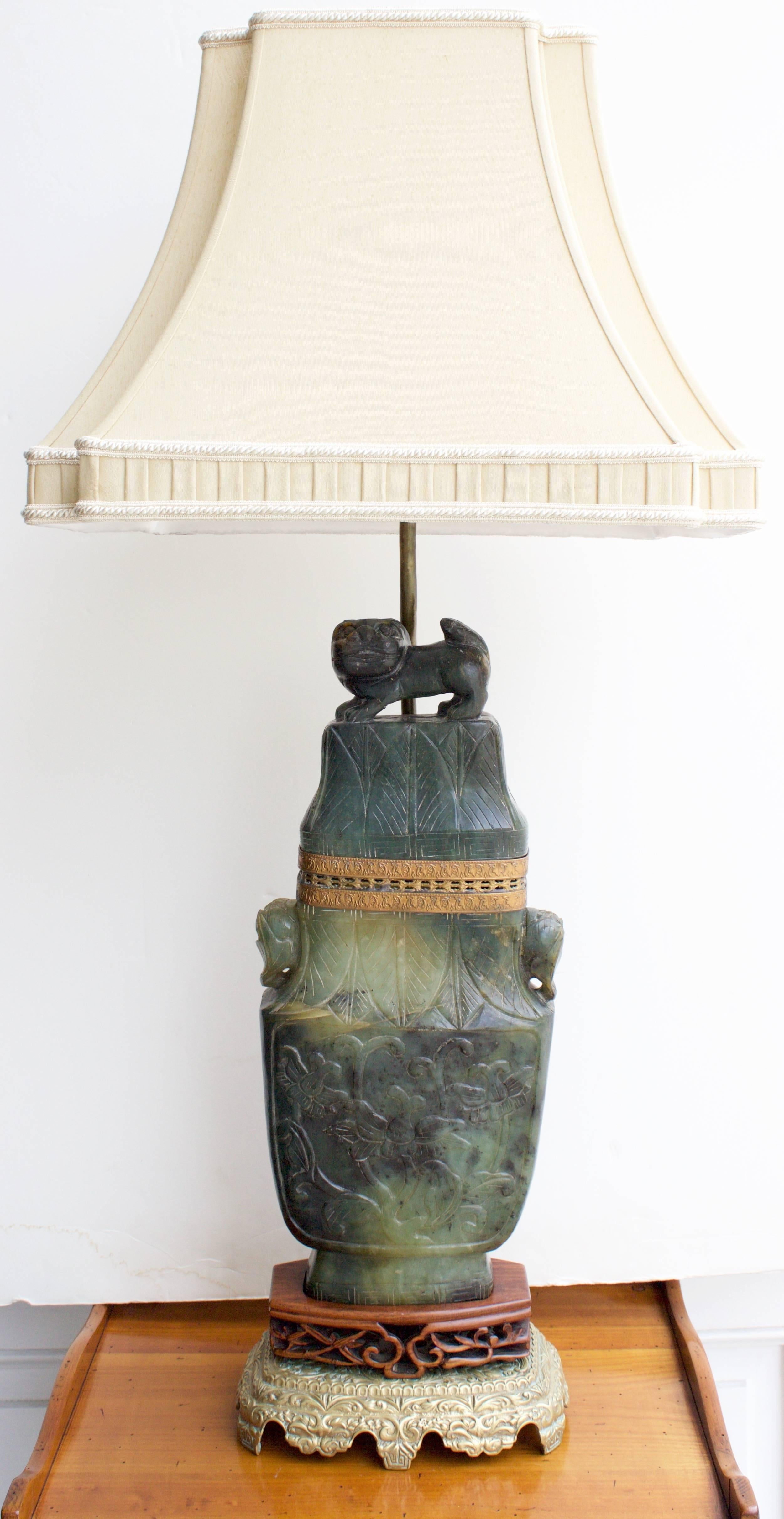 Rare Antique carved jade lidded urn table lamp .Mounted on a highly carved wood support resting on a bronze base.The jade carving is on both sides and represent flowers and leaves.The lid is surmounted by a Foo Dog.
newly rewired with a regular