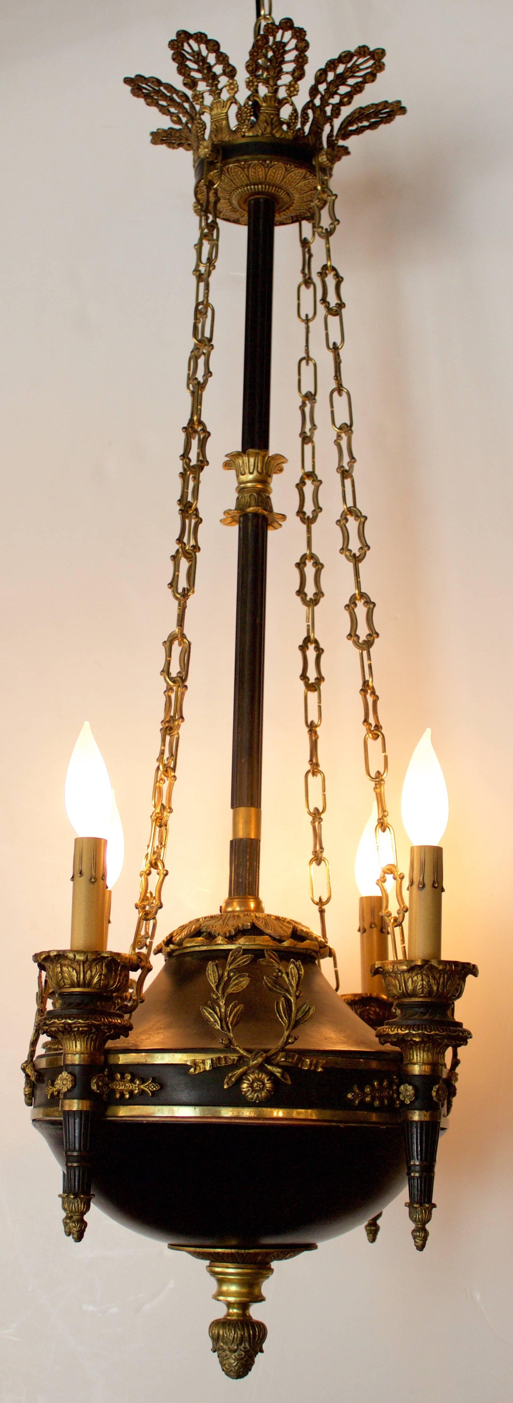 Interesting chandelier from very early 19th century in patinated and gilded bronze supported by a central shaft in bronze too and surmounted by a gorgeous 