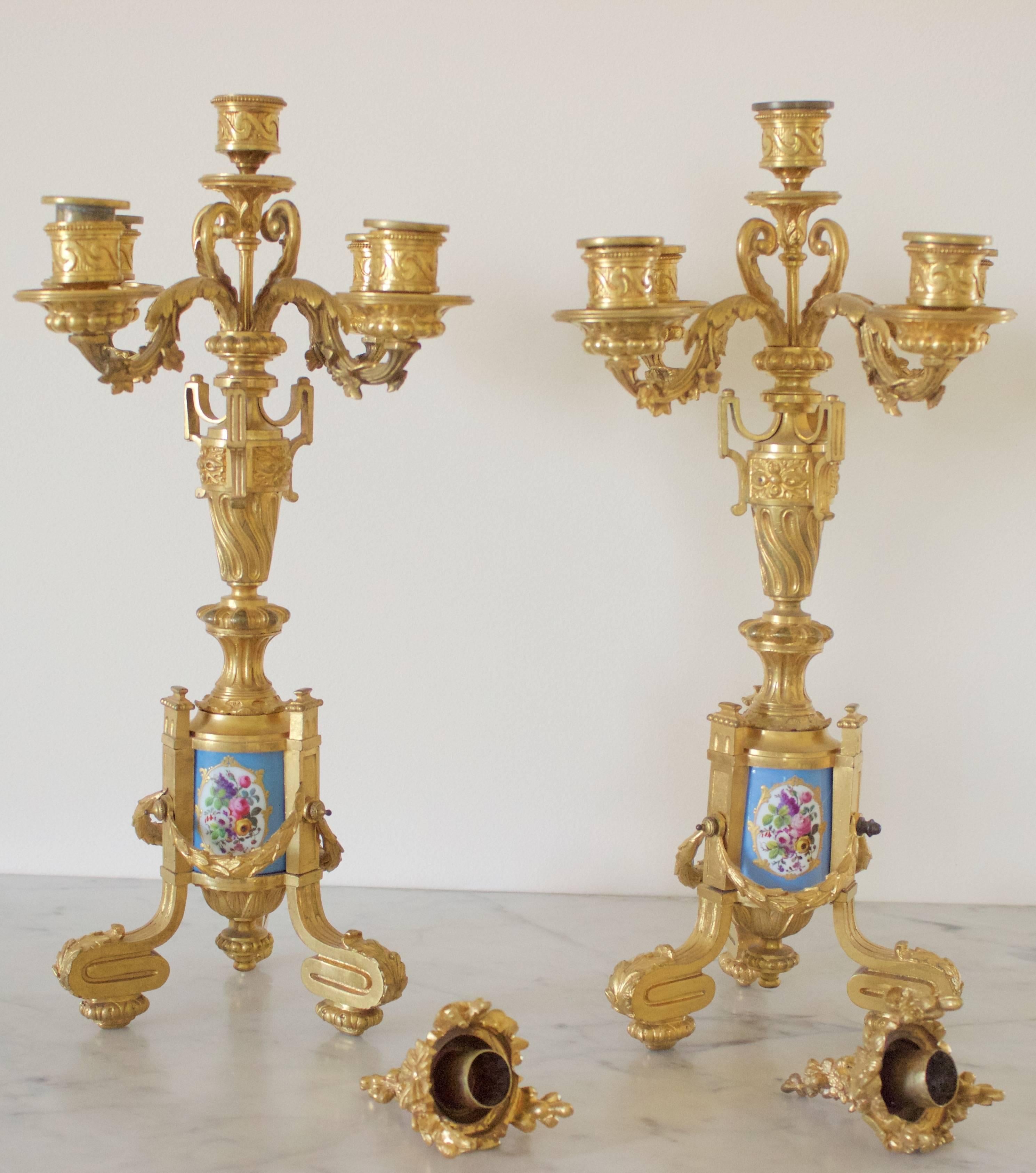 Exceptional and magnificent pair of finely chased ormolu gilded bronze candelabras with five lights above spiraled urns. The base is a tripod mounted around a Sevres famous 