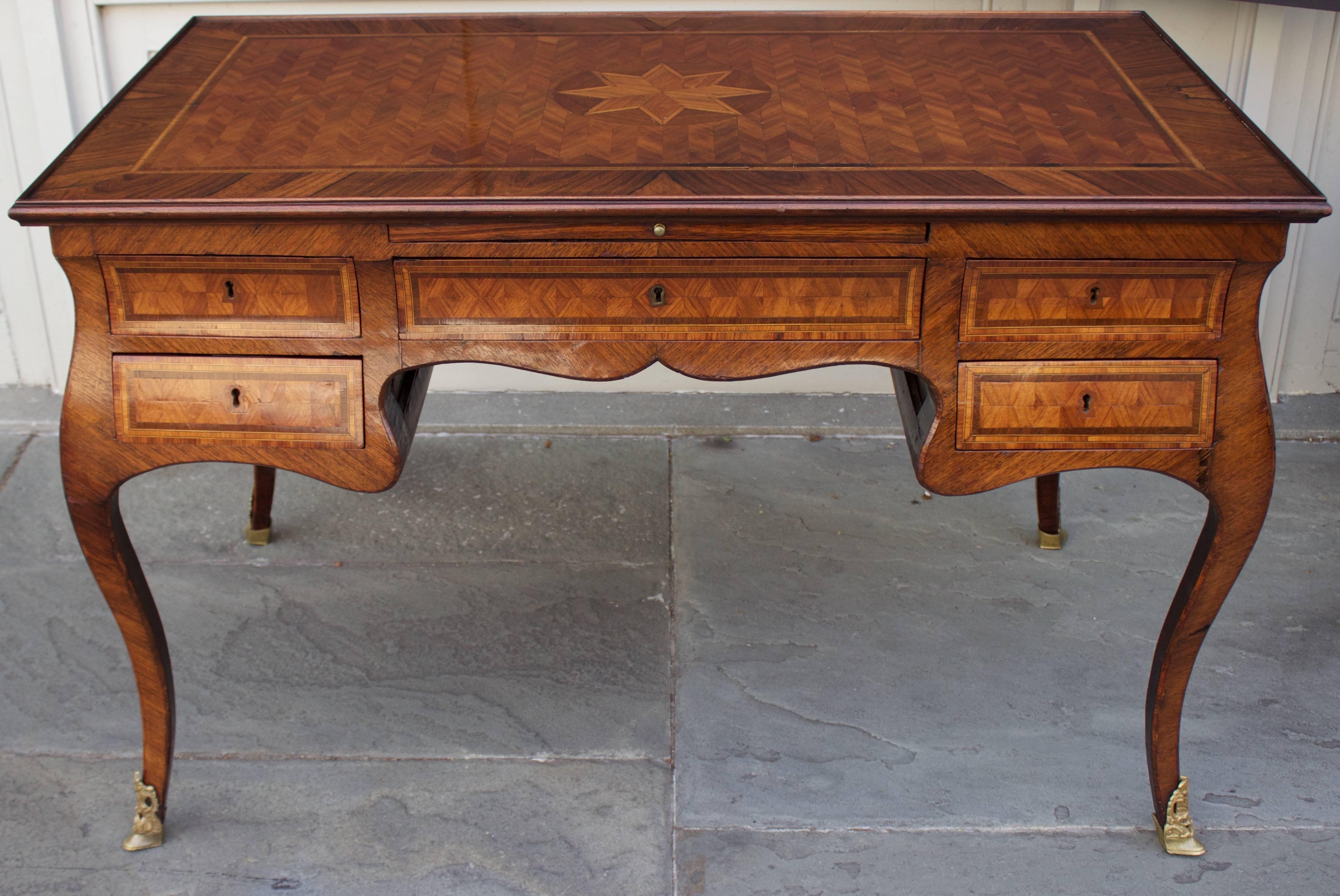 During the 18th century. Europe emulated the French court and this desk shows clearly the influence of the Louis XV period.
Parquetry inlaid and raised molded edge top above five drawers and a central pull-out covered with green felt. False drawers