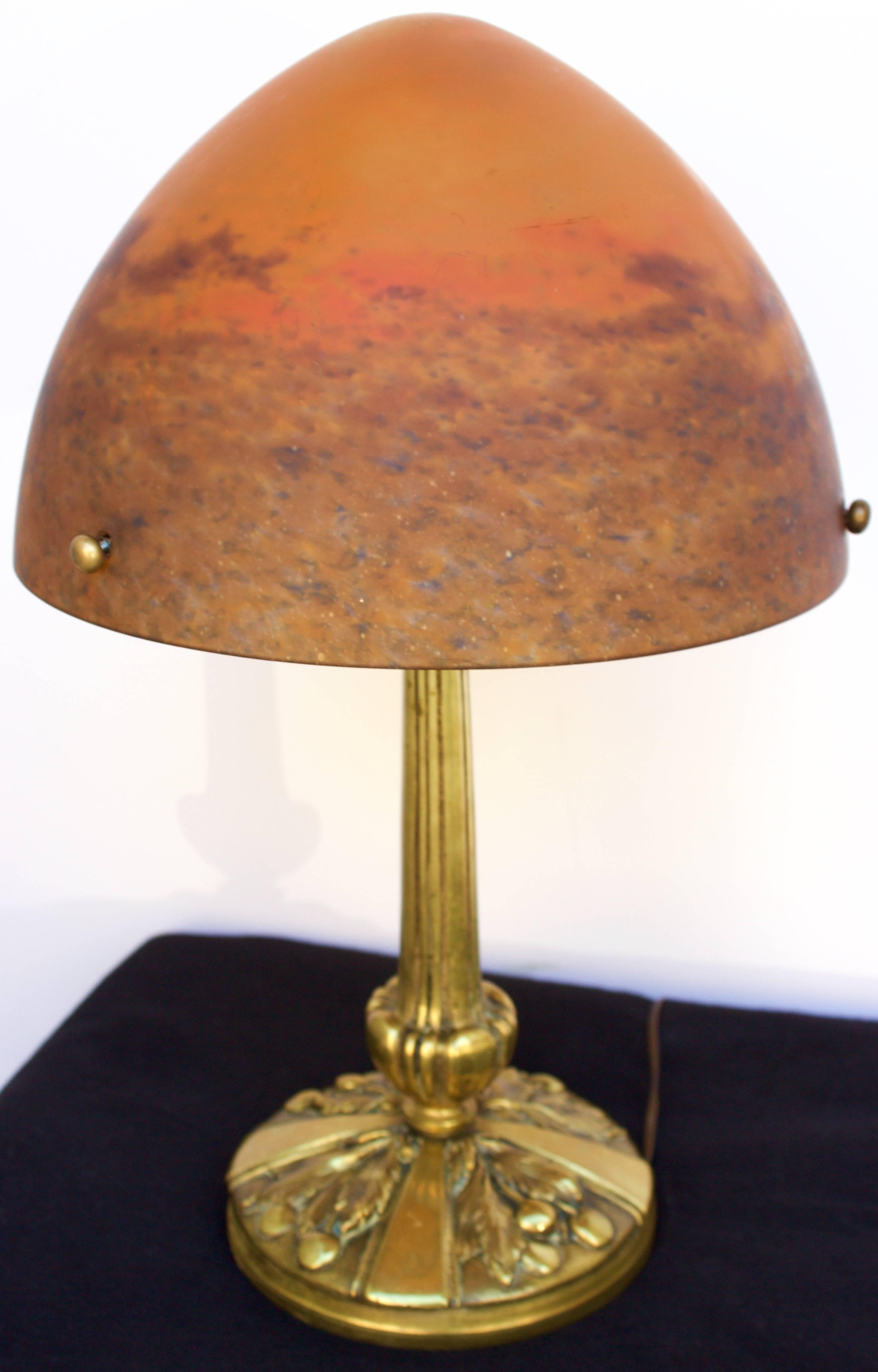 This very rare and exceptional table lamp has a gilded bronze base and stem holding an handblown marmorean glass shade shaped as a parabolic cone. The glass is made of two layers ,has been fire polished outside and etched inside. It carries the