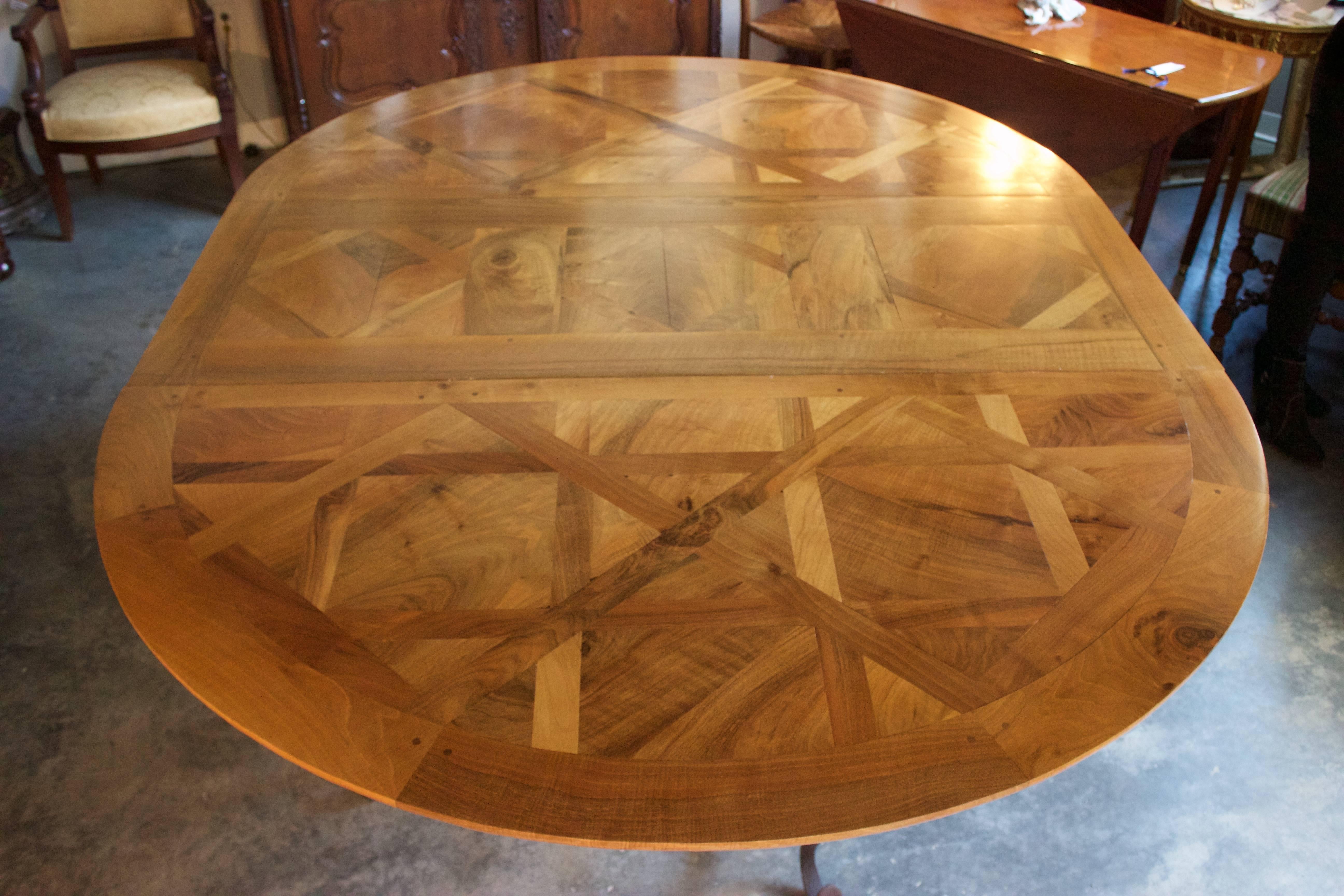 Beautiful parquet top round dining table made of reclaimed French walnut and iron. Top is newly constructed of reclaimed French walnut which rests on a beautiful scrolled wrought iron base. If, and when needed the table has a central leaf of