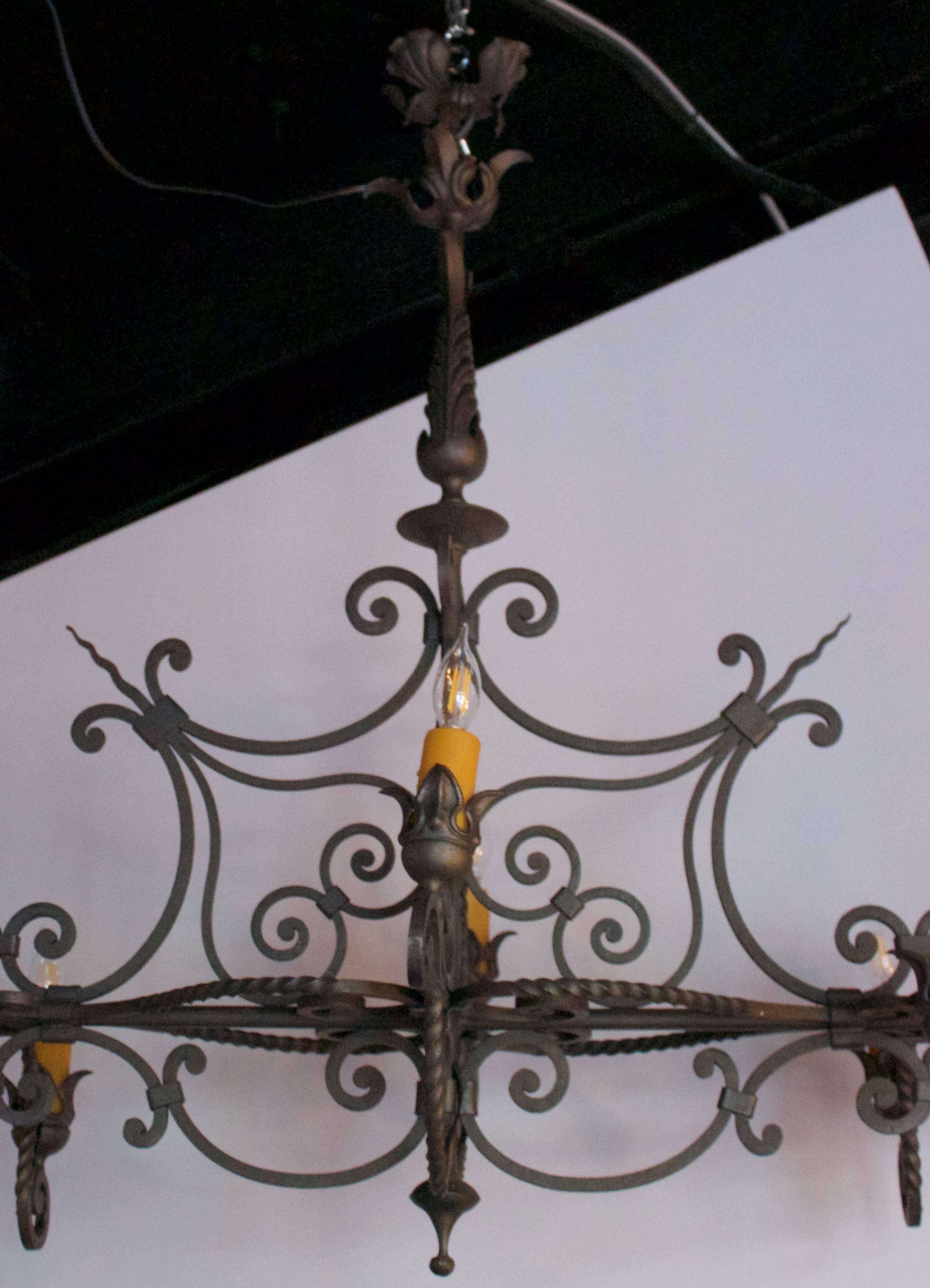 Beautifully designed wrought iron chandelier featuring eight lights with twist and scrolled decor. Black painted iron, wax candle sleeves. Rewired for US standard.