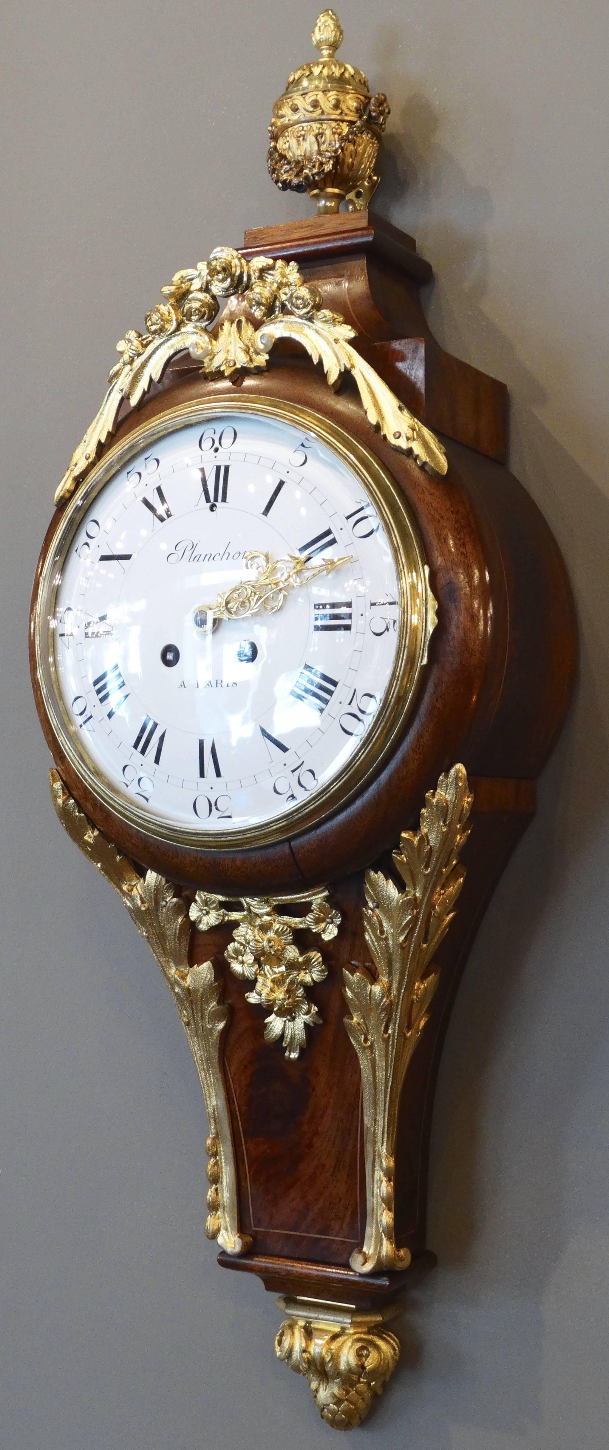 Extremely decorative clock (named Cartel in French) in mahogany inlaid with gorgeous chiselled and gilded bronzes representing Roses and acanthus leaves. Top is surmounted by a bronze doré' 