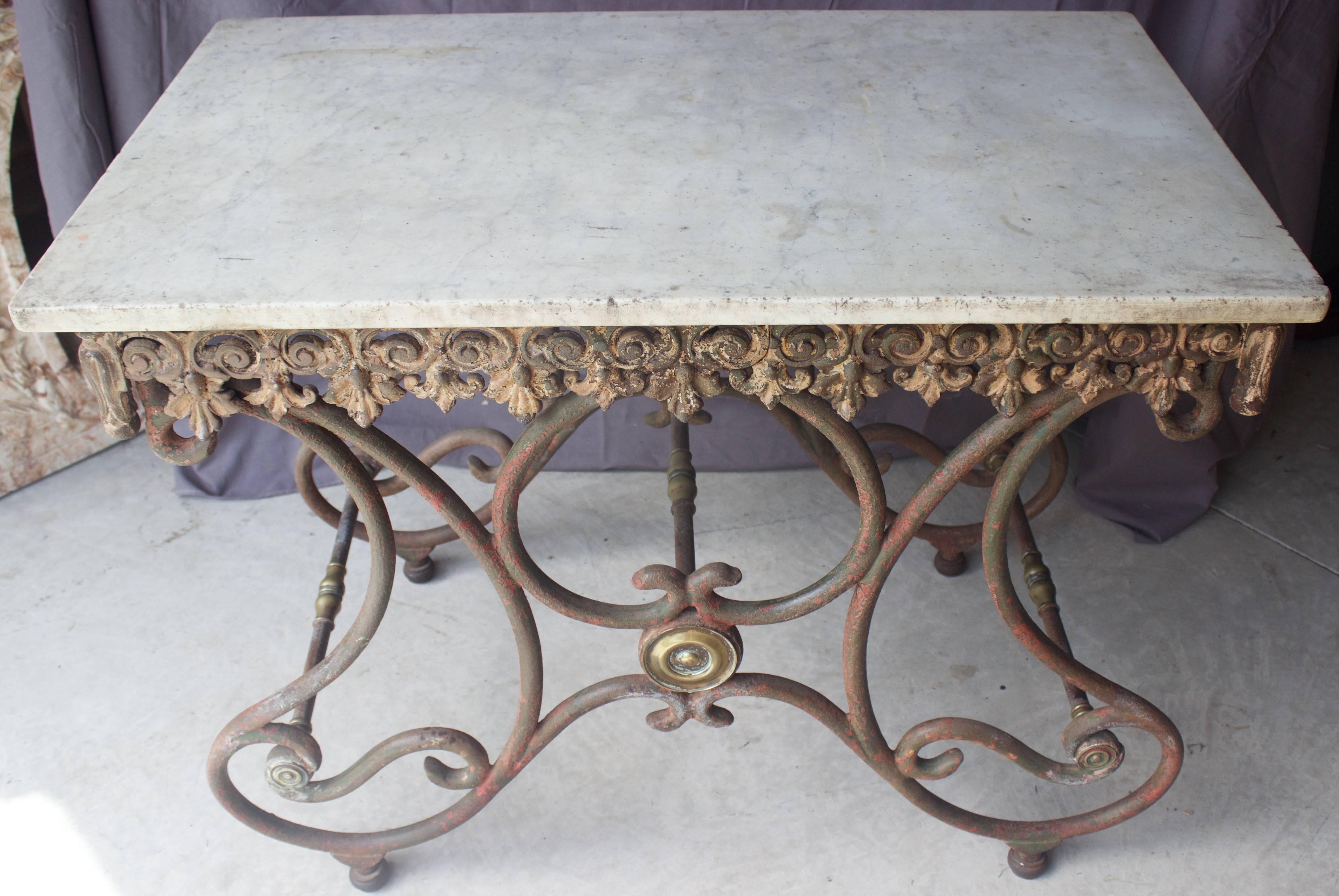 Napoleon III, rare and attractive French butcher table from the mid-19th century. Scrolled forged iron legs highlighted by brass finials and turnings on each of the three crossbars. Nice cast iron frieze Decor on three sides to enhance the one inch