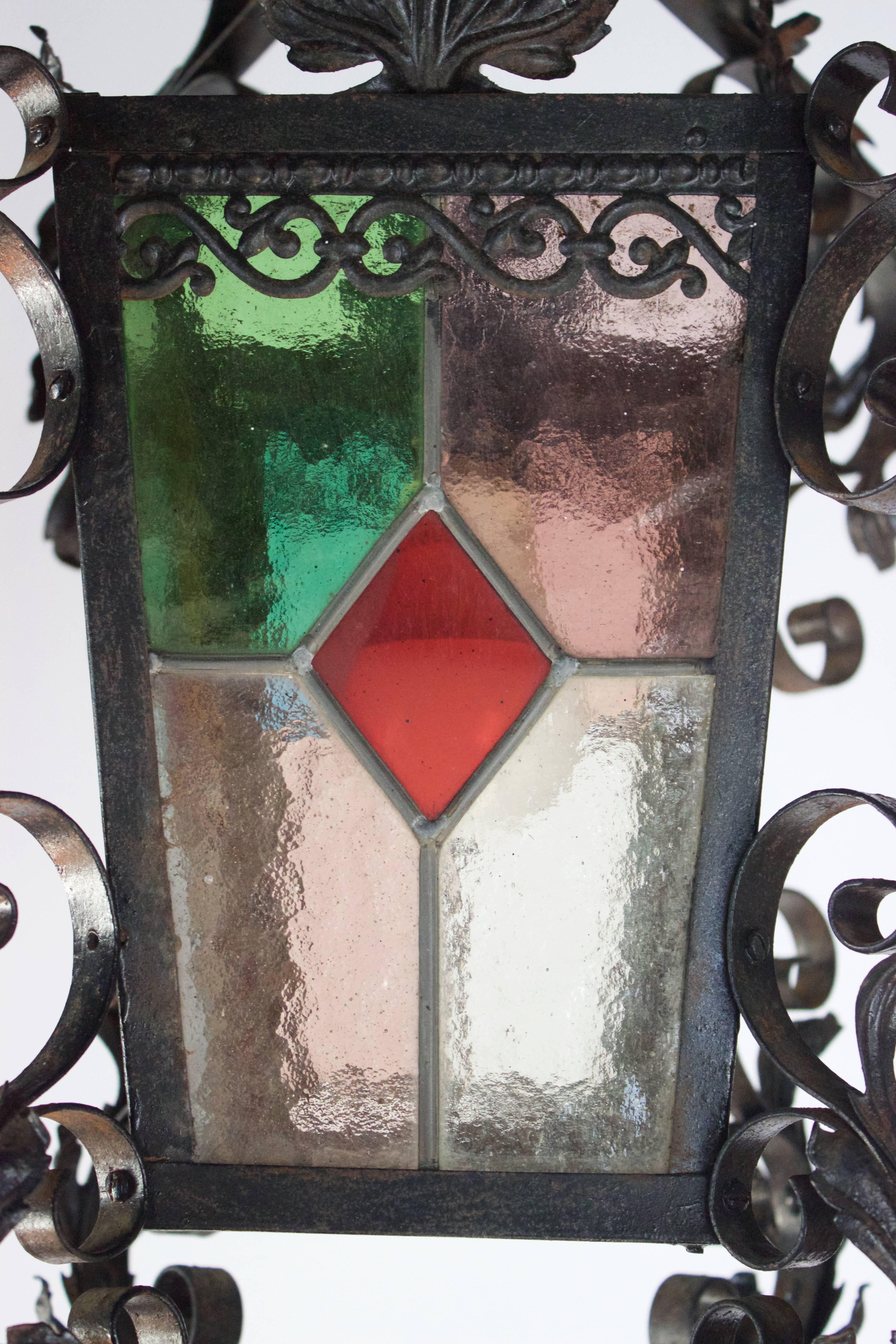 Elegant hand-forged iron lantern with colorful glass panels on each its four sides, made circa 1900 .
Has been newly wired for the USA for a single bulb with any wattage wished as bottom and top are open space.
This lantern will look great in an