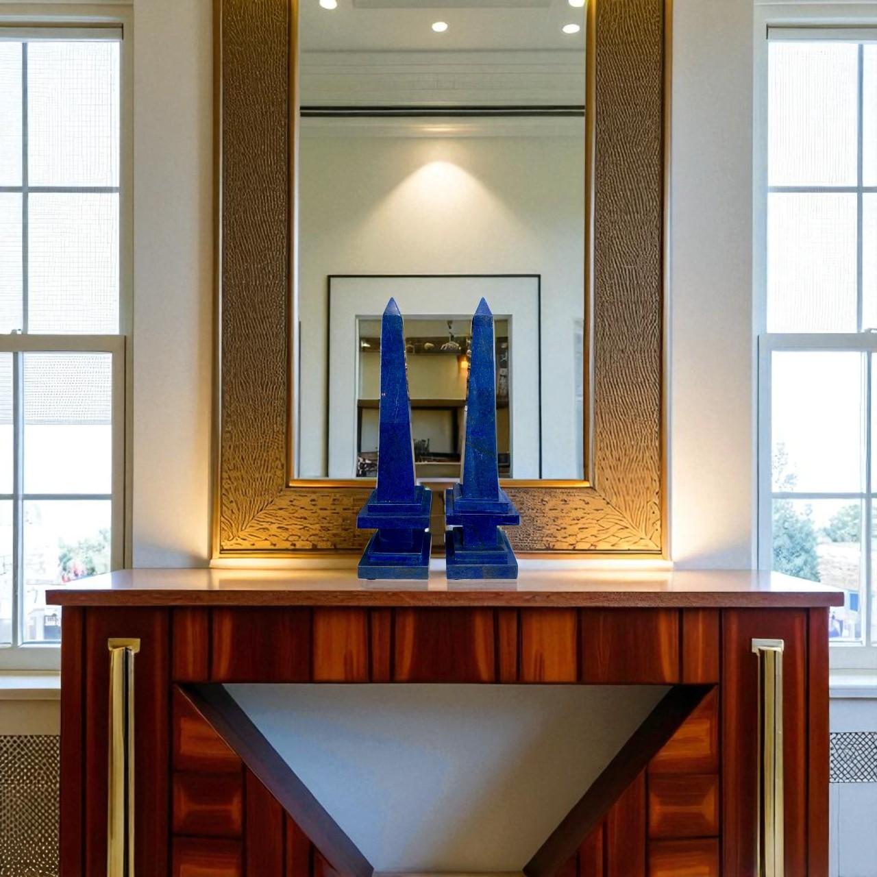 Ajoutez une touche de brillance minérale et d'élégance intemporelle à votre intérieur avec cette étonnante paire d'obélisques en lapis-lazuli, sculptés dans une pierre d'un bleu profond et vibrant rehaussé de délicats reflets dorés. Le lapis-lazuli