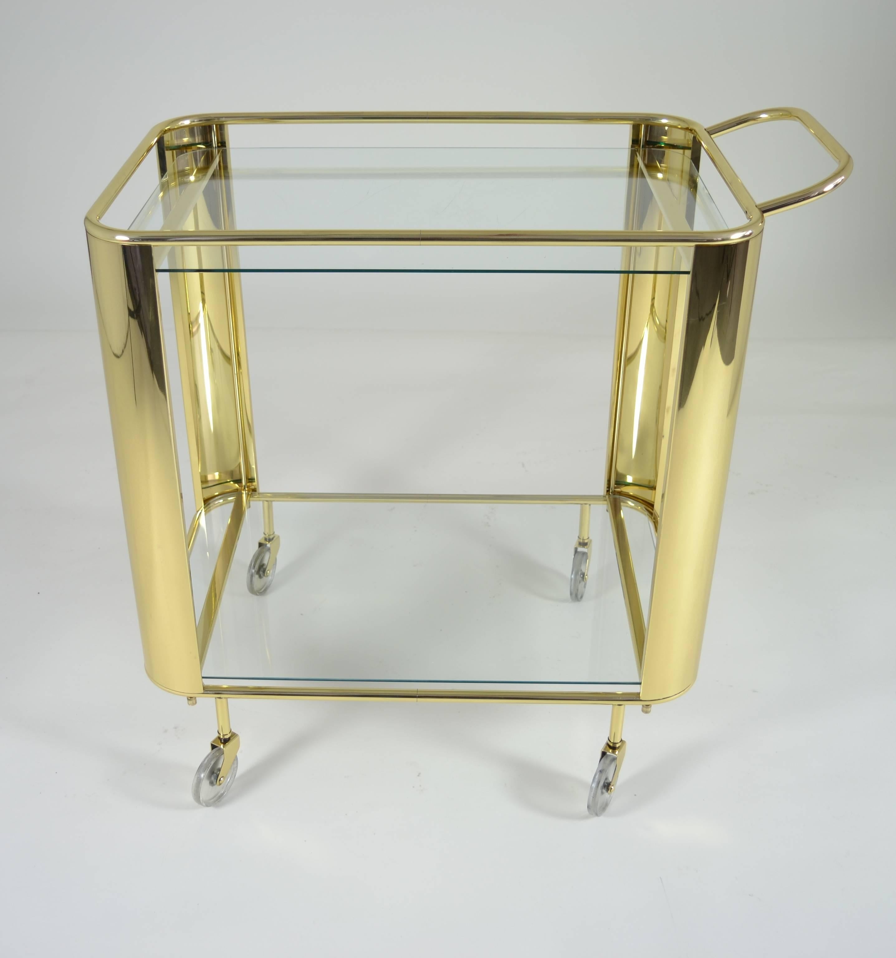 Sleek curves and simple lines, a solid brass cocktail cart with two glass surfaces. Newly polished and lacquered. Great style.