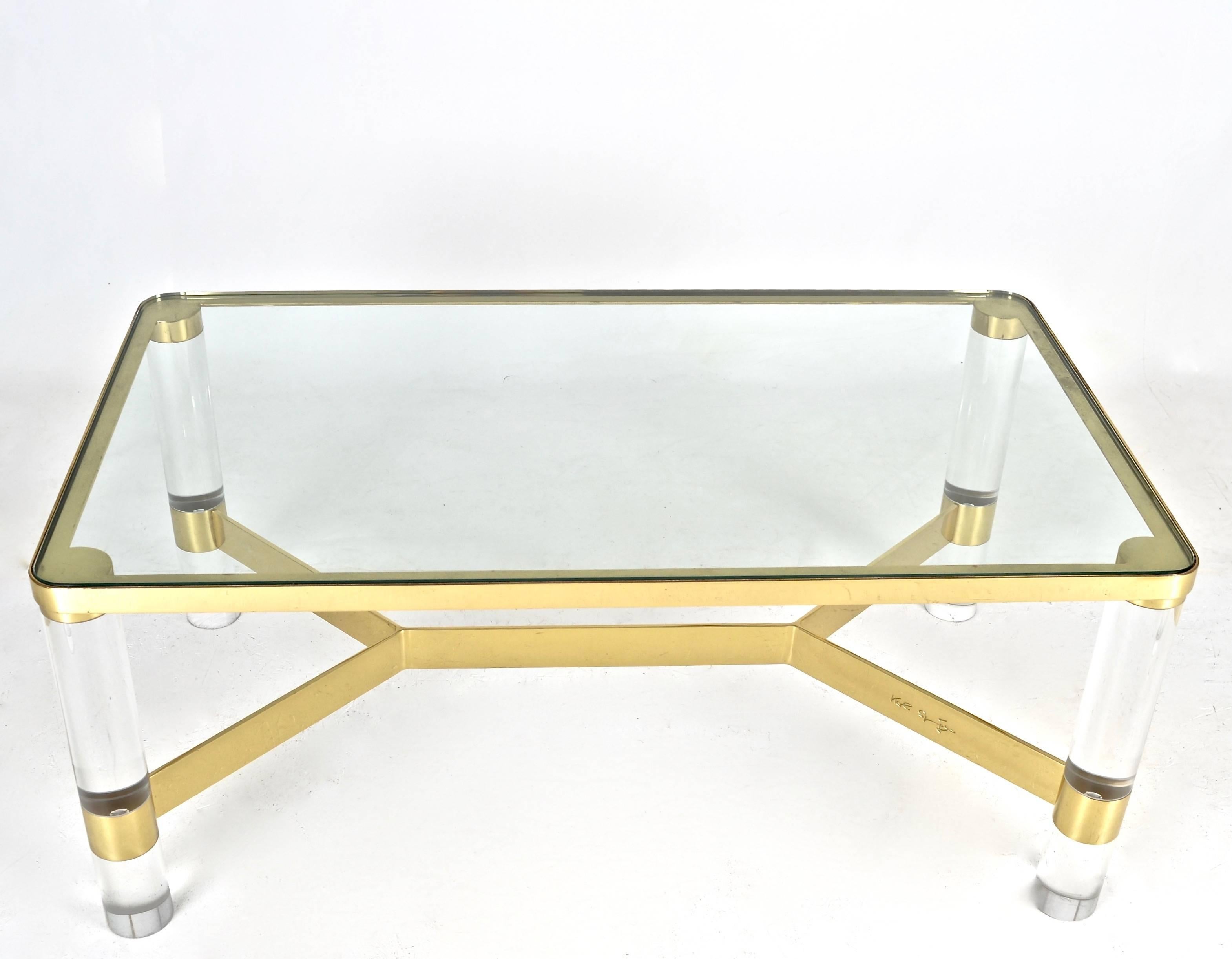 In excellent condition, newly polished and lacquered. Featuring distinctive design and incised Karl Springer signature. Heavy glass top set into polished brass frame. Thick cylindrical Lucite legs. 