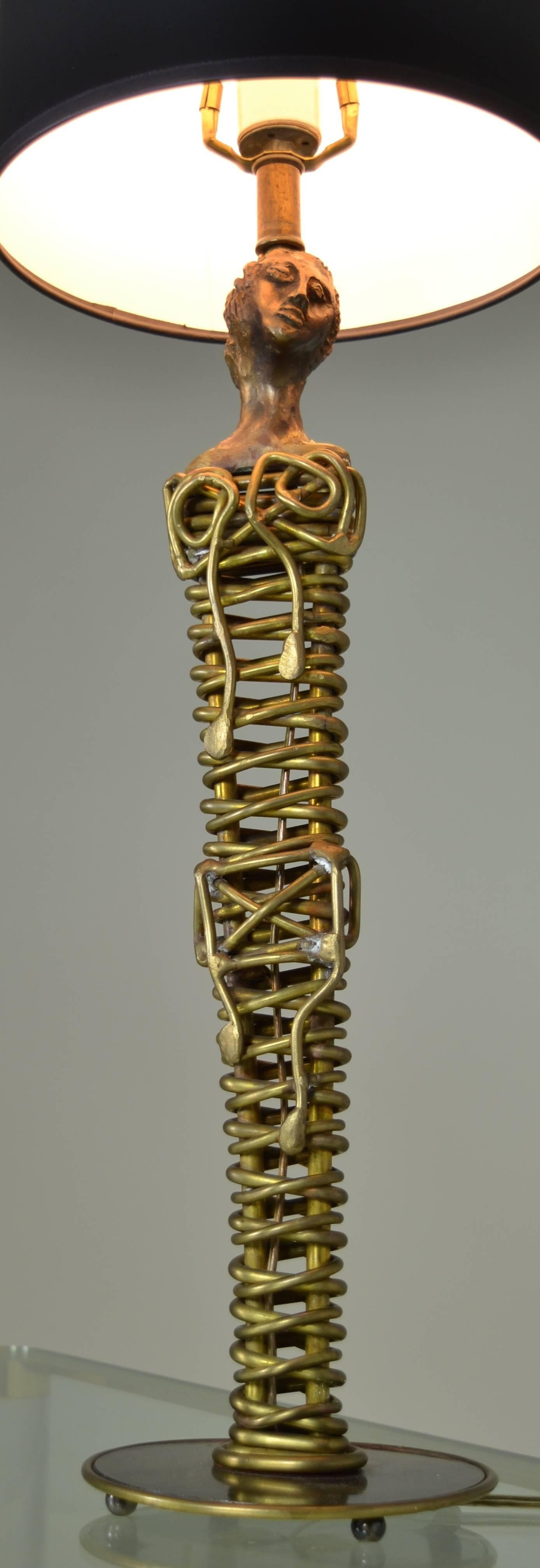 Skeletal and haunting, a lamp base made of bronze metal and gilt plaster (head). Base is polished and distressed steel with copper edge. Signed Villa, dated 1991. Mario Villa, born in Nicaragua, now lives and works in New Orleans. Measures 6.5