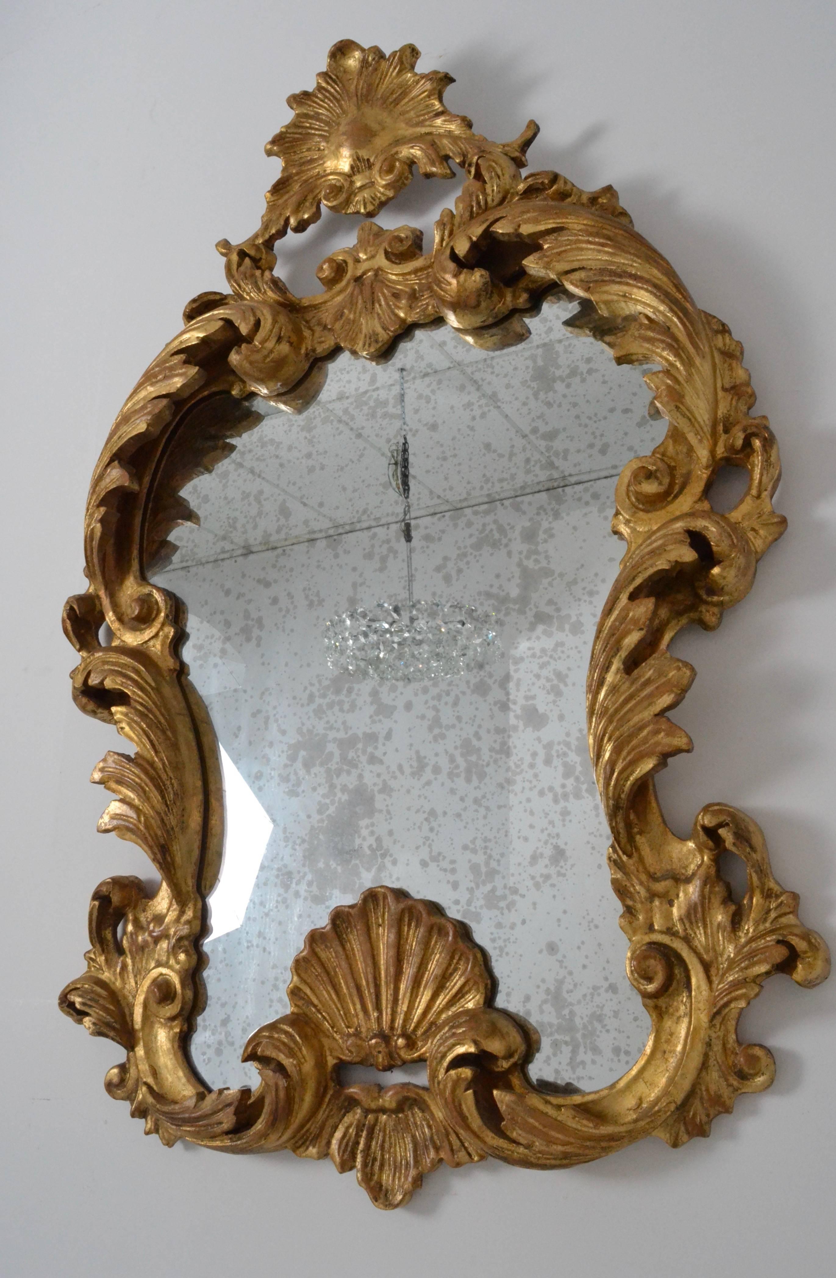 Beautifully figured Rococo style mirror with deep and fine carving. Warm gilded finish.