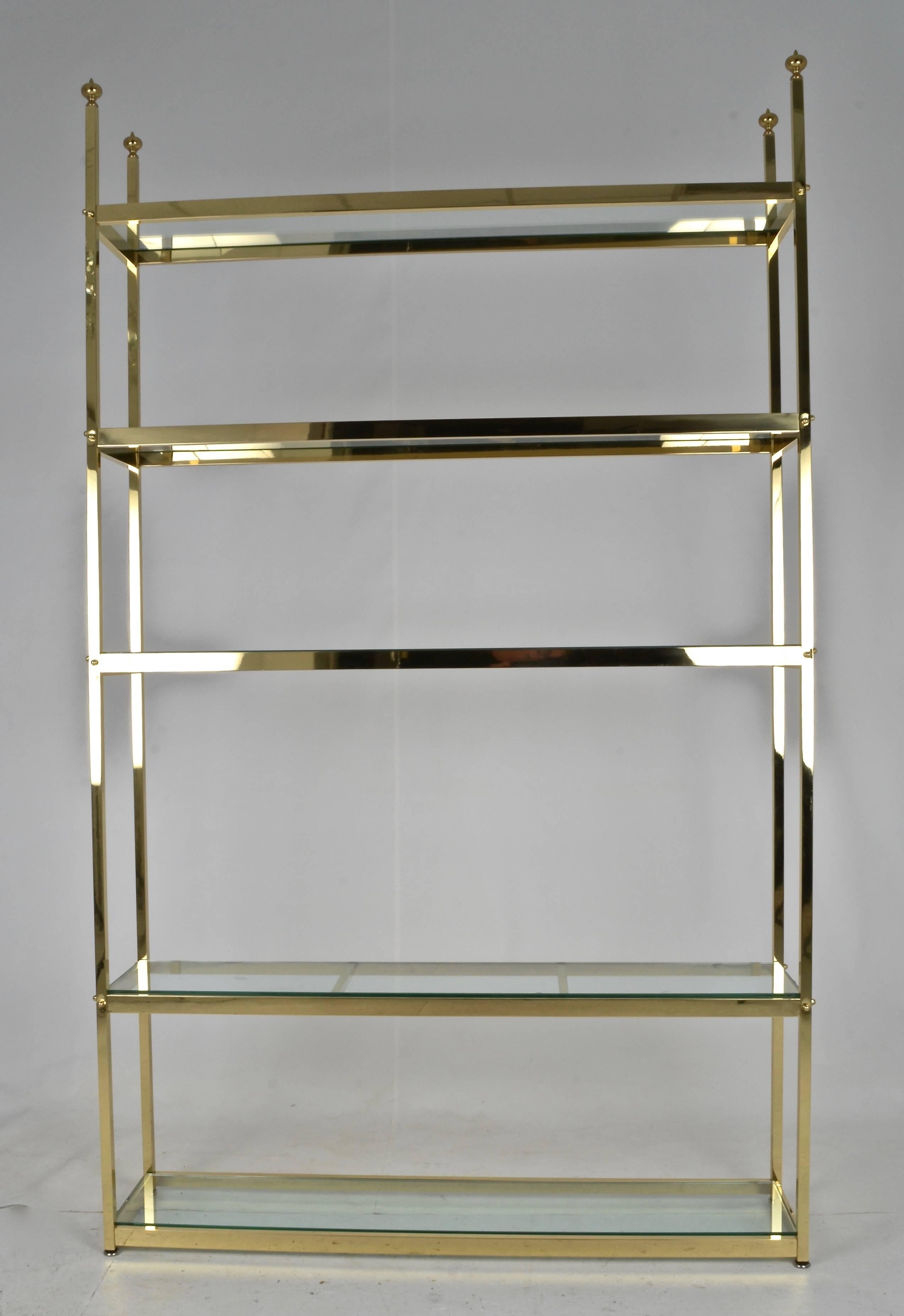 Solid brass and quality construction, a large size étagère at 49" wide. Heavy glass shelves. Newly polished and lacquered.