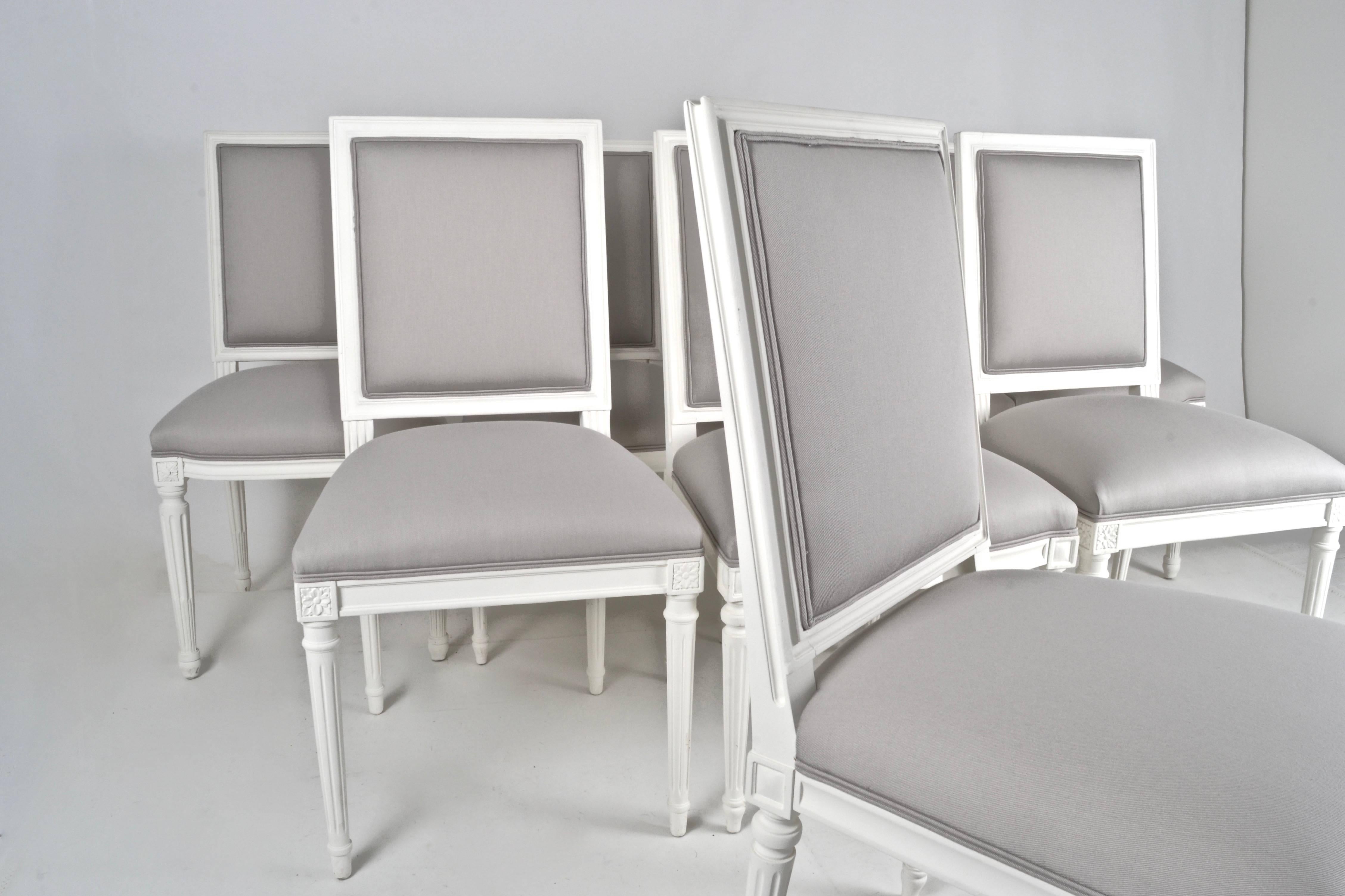 Newly lacquered and upholstered in dove white matte finish with dove grey cotton covers, a great set of eight dining chairs. All the same back height and seat height, there are slight design differences between the chairs. Four of the chairs are