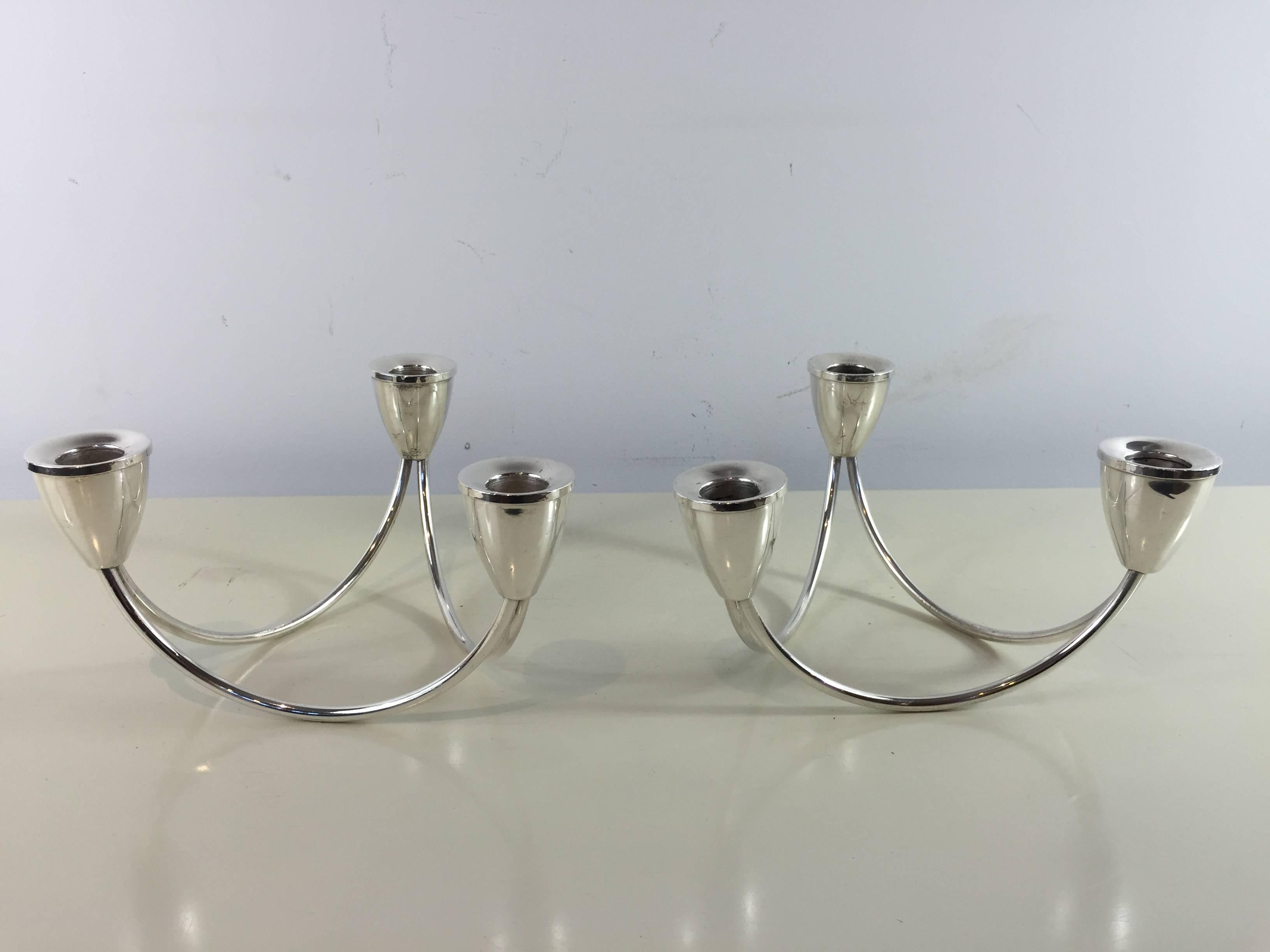 Pair of sterling Mid-Century Modern candelabra, each one of triangular form, with three lights and raised on a curved sterling rods, can be used individually or combined to make a circular six-light centerpiece.

 