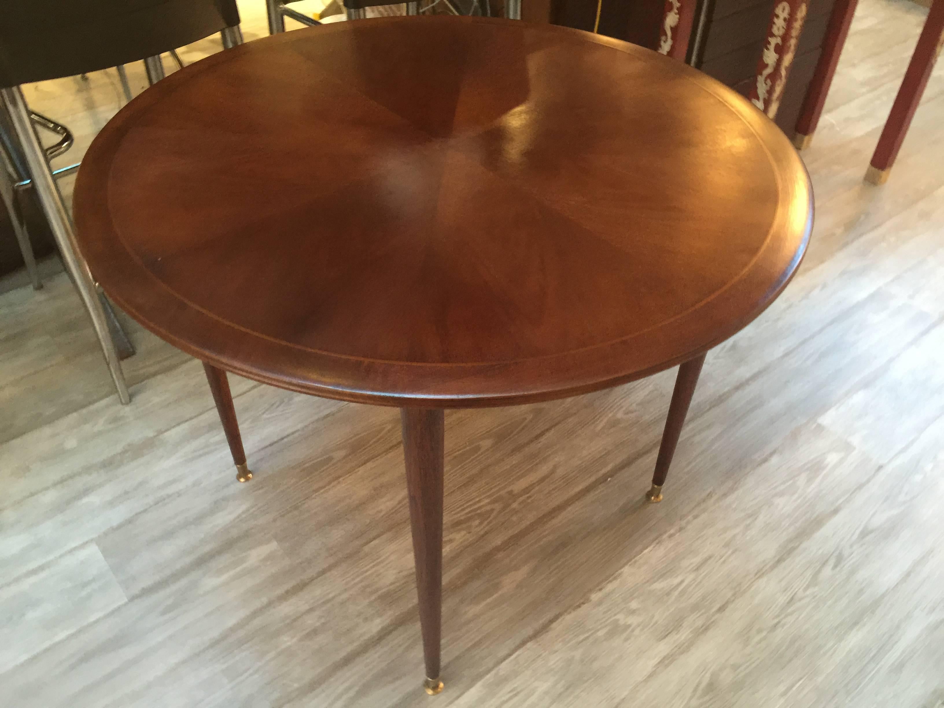 An elegant Gio Ponti style center table by Singer & Sons, round form with beautiful inlaid wood top with brass banded border and brass feet caps.
