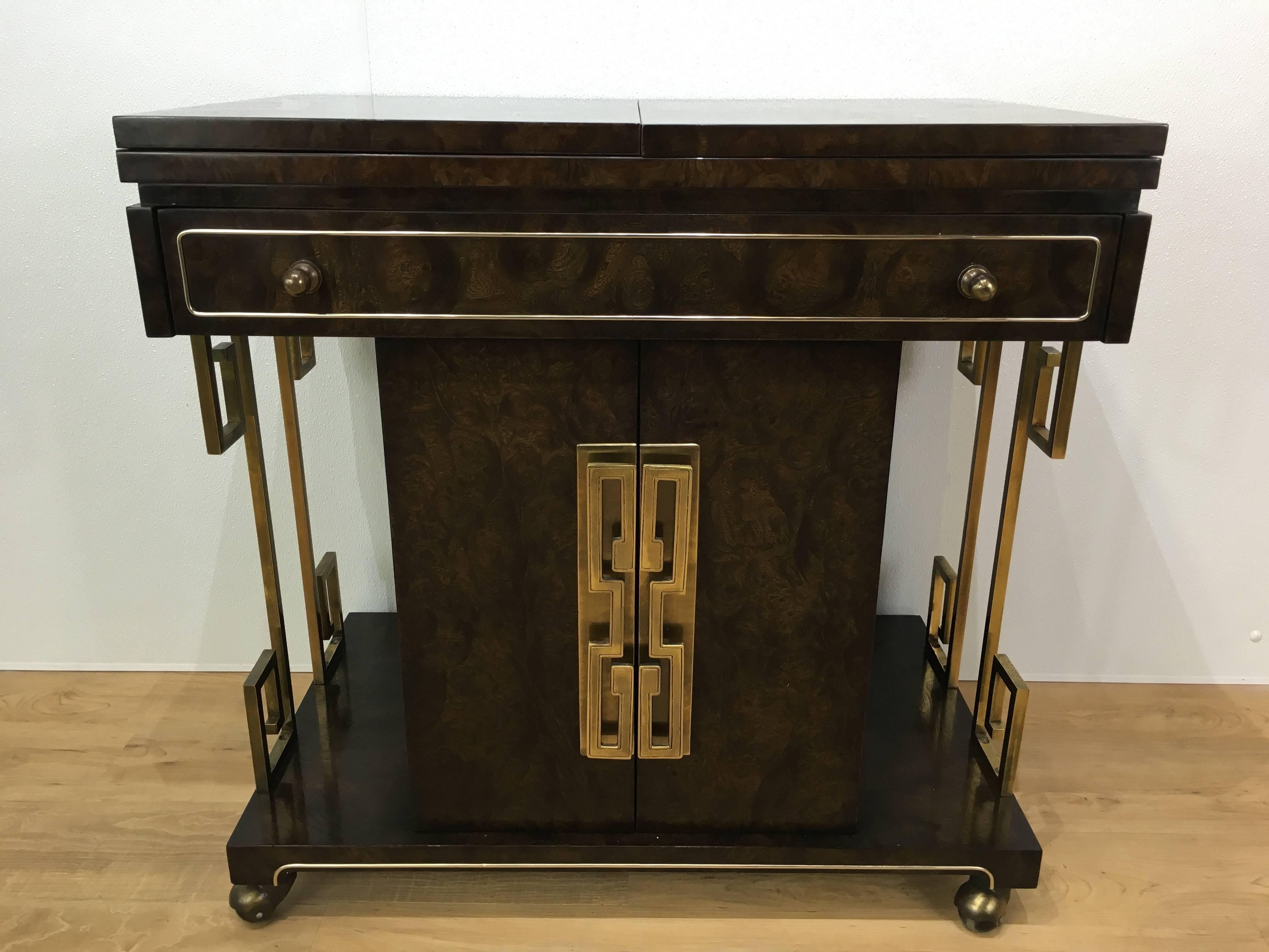 Mastercraft Greek key dry bar, of expandable rectangular form, beautiful variegated burl wood with stylized brass Greek key mounts. Fitted with one long drawer and two lower doors, raised on brass castors. Length of bar with extended top measures
