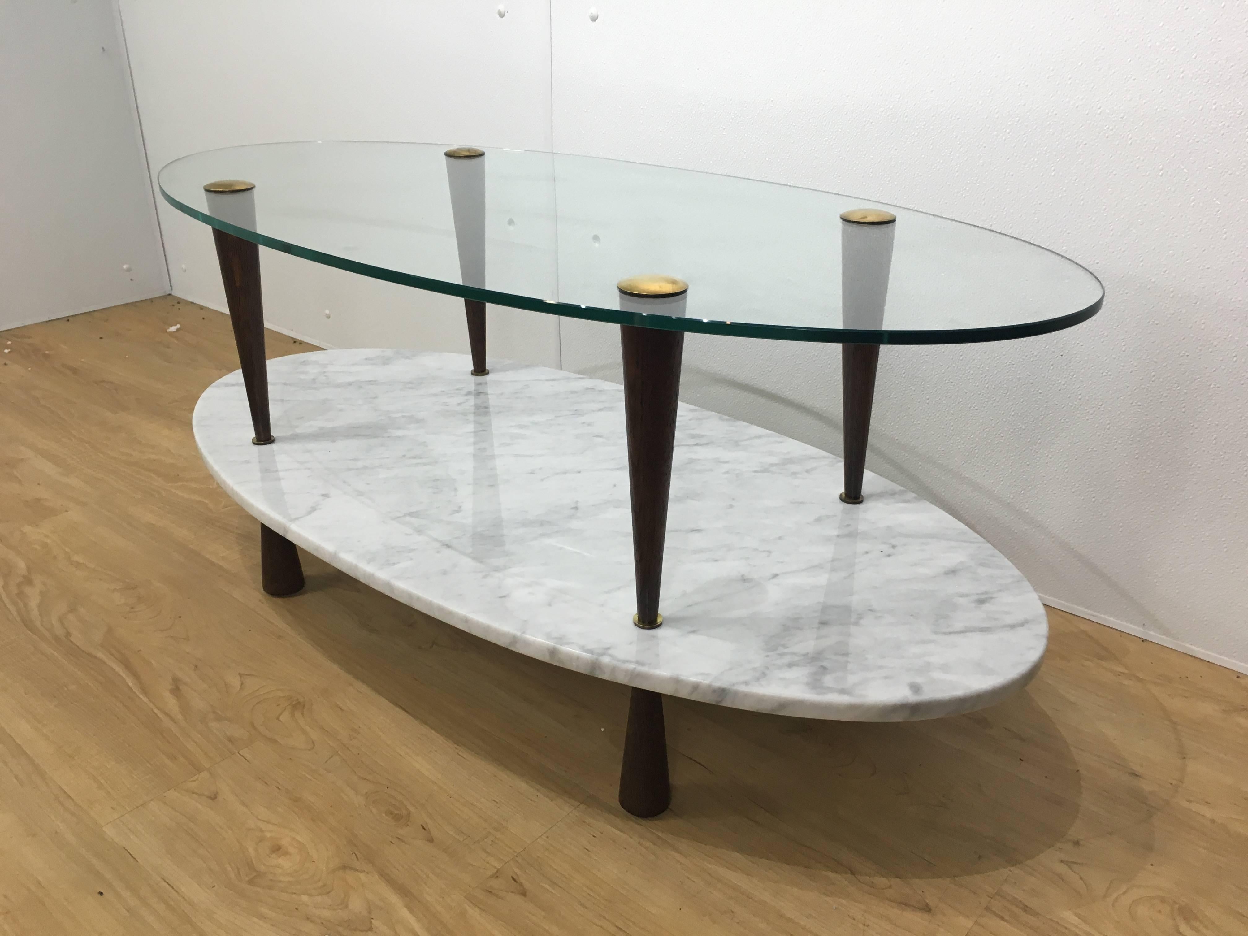 Italian two-tier marble and glass cocktail table in the manner of Gio Ponti with oval glass top and brass capped conoid legs, lower Carrara marble shelf. Expertly finished.
We have the matching pair of side table in stock (inv. # 1951). Please