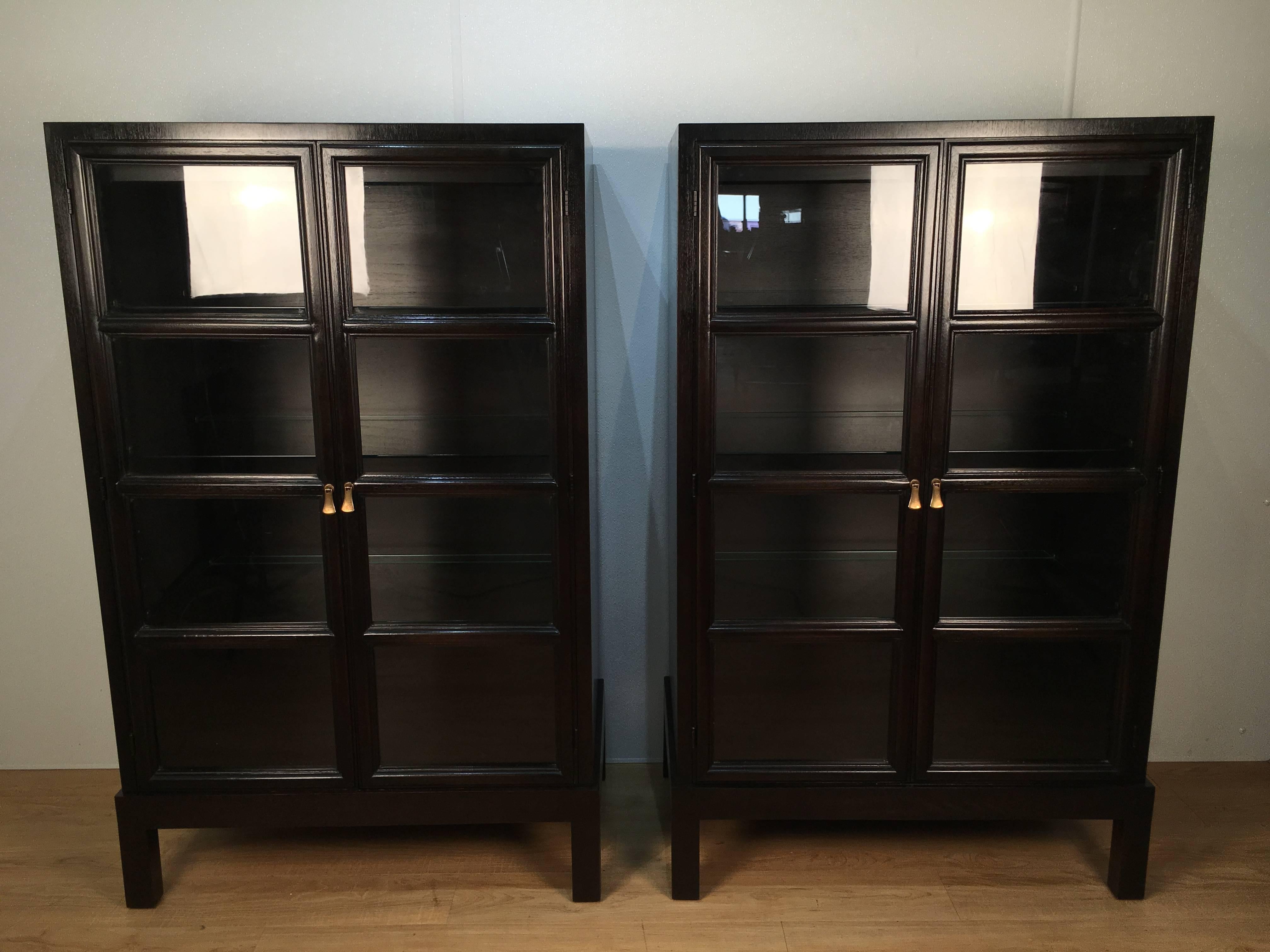 Pair of Widdicomb mahogany glass front  bookcases/ cabinets, each one with twin four panel glass doors, with three adjustable glass shelves and one interior light.
Raised on a conforming straight leg base.