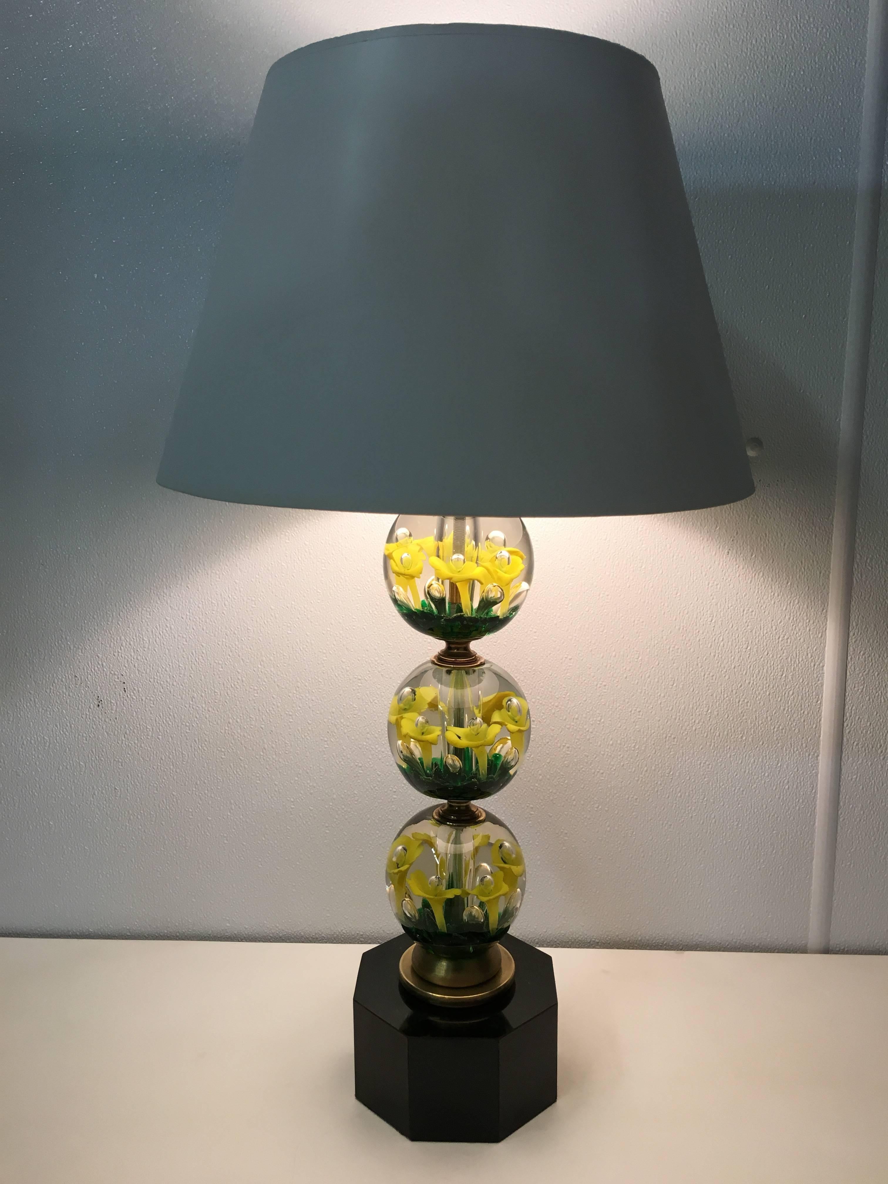 Mid-Century paperweight glass lamp by the St. Clair Glass manufacturing family of Indiana. With three tiered orbs with vibrant yellow and green flowers suspended in the glass, raised on a octagonal plinth base. 
Shade for display purposes only.