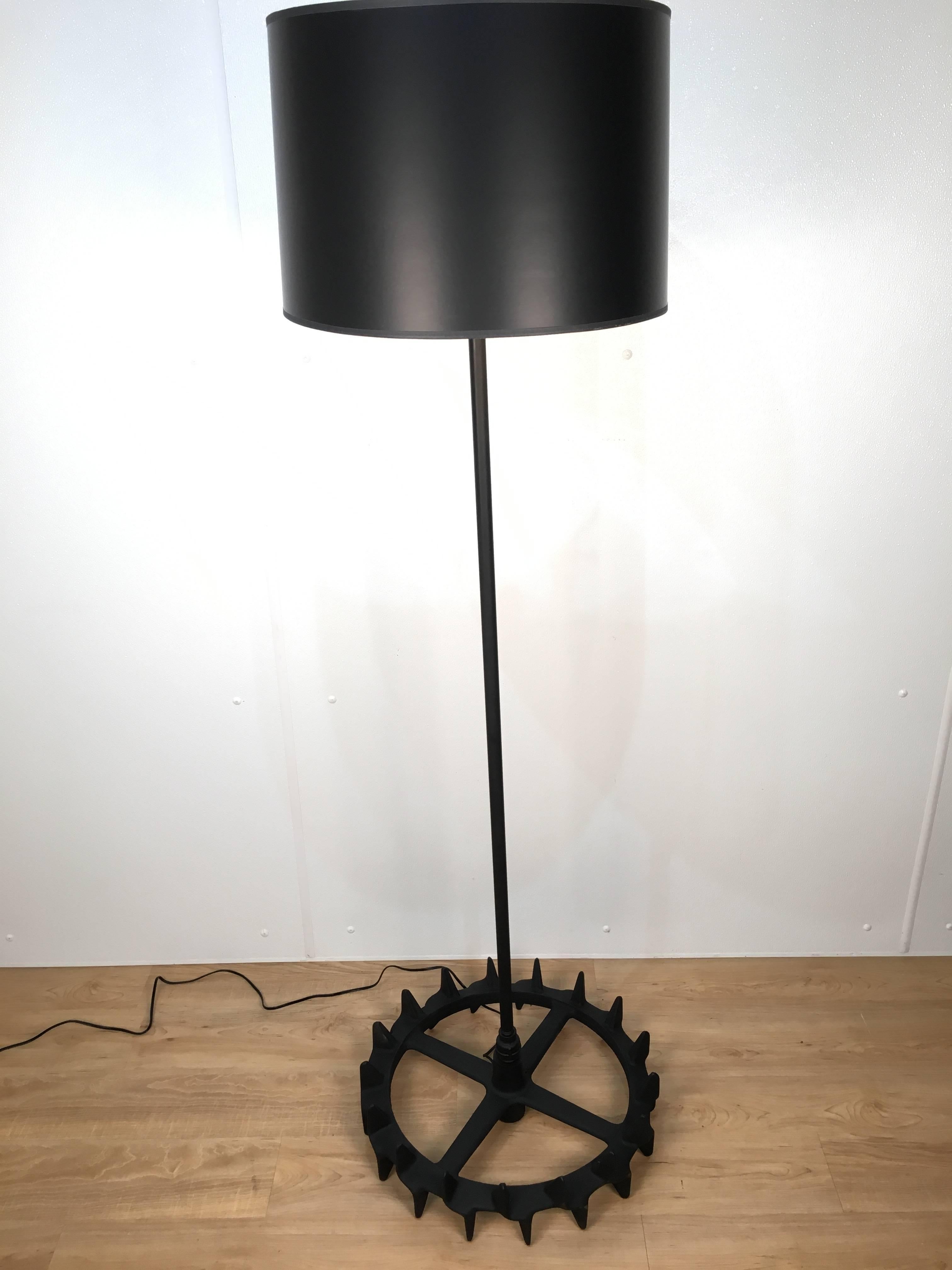 Pair of heavy industrial iron gear floor lamps. One of a kind repurposed gear base and iron body. Black powder coated finish and newly wired. Alternating gear tips have rounded ends and are not sharp. Each gear is stamped and dated 1926. Shades for