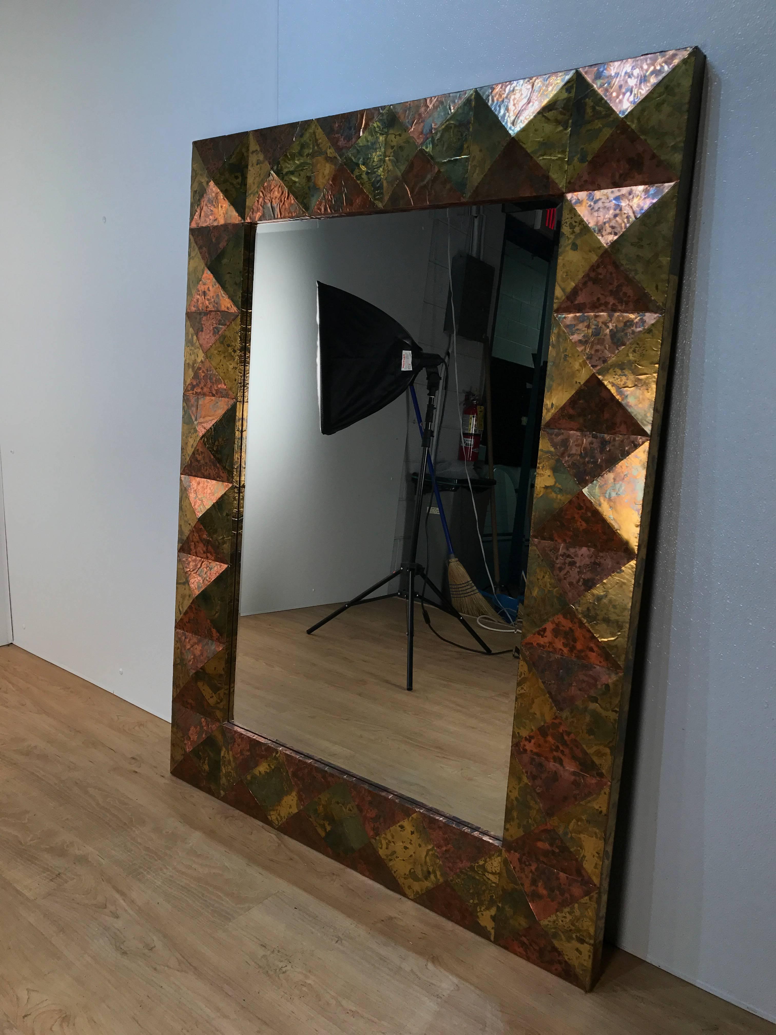 Large copper and brass clad faceted mirror, of rectangular form with continuous pyrmidarial surround.