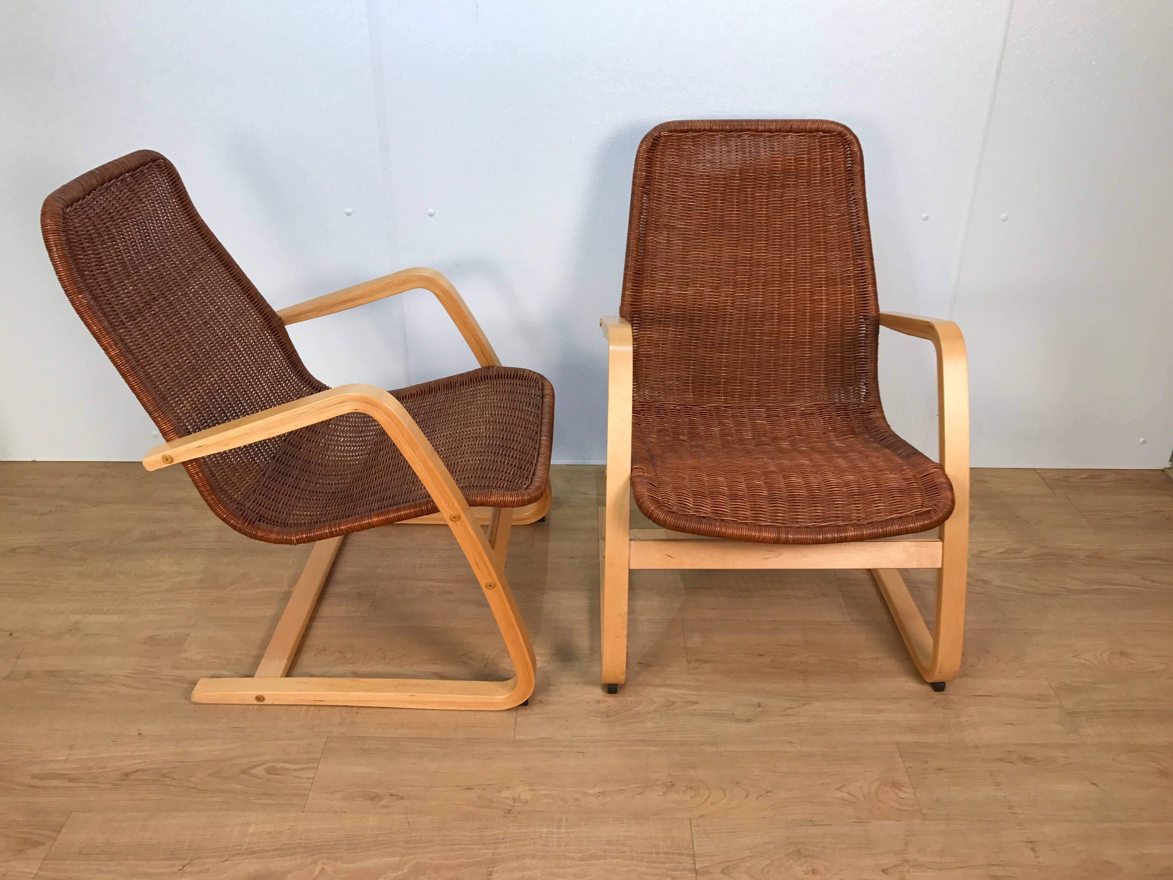 Pair of Alvar Aalto style wicker lounge chairs, each one with rich dark brown wicker seat and back rests on a blonde wood cantilever frame. Very comfortable pair of chairs with a little "bounce". The seat is 18" wide. A great pair of
