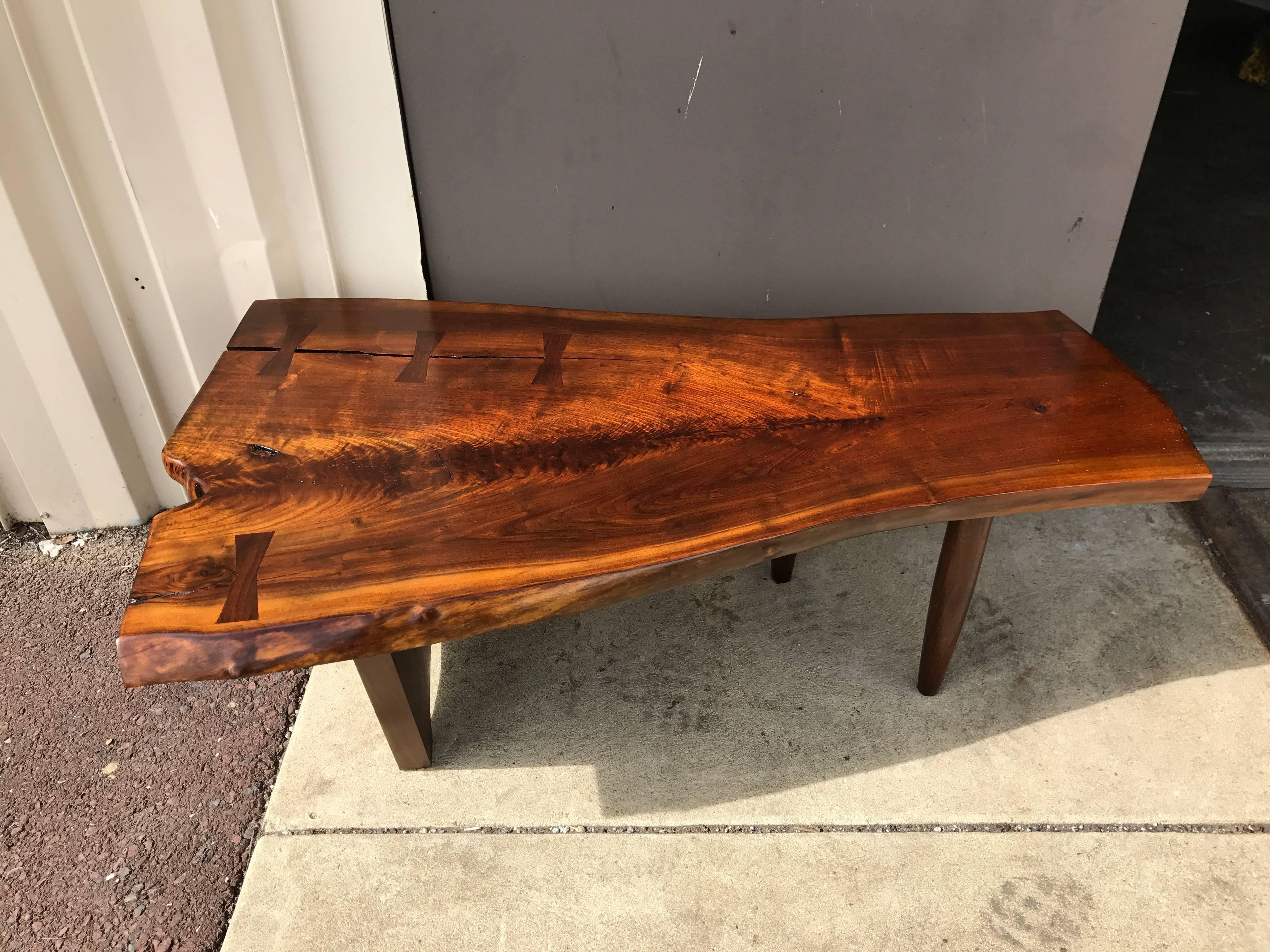 Nakashima style live edge walnut slab coffee table, with four inset butterflies, knots, and fissures.
 