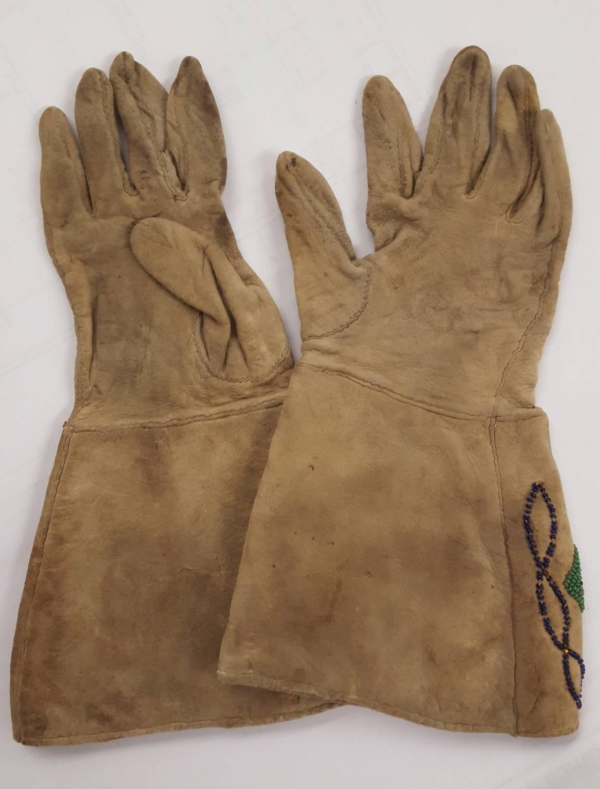 A pair of (circa 1890-1910) Native American Plains gloves, possibly for a woman. Made of deer skin with glass bead designs on the cuffs and top side of gloves.