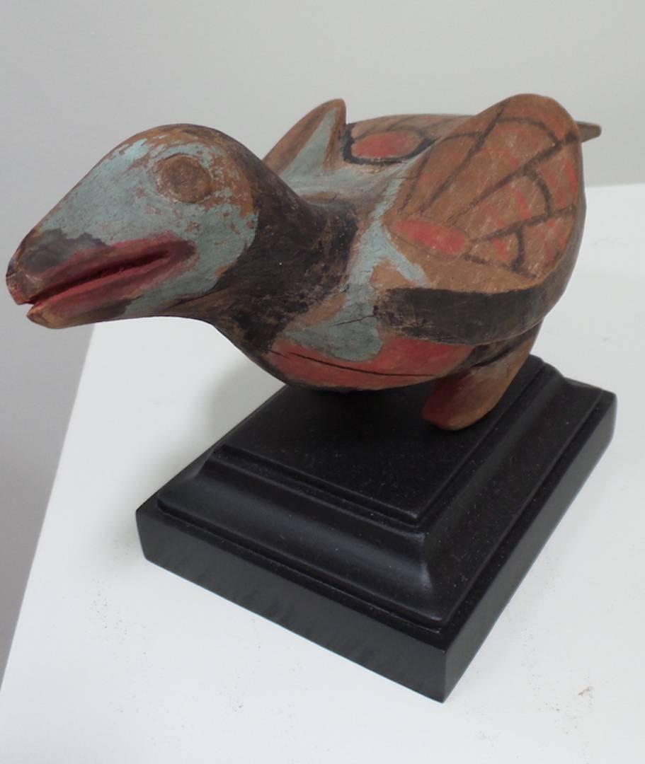 A Northwest Coast Native American carving of a bird (perhaps a Raven), of painted wood, circa 1900- 1920, by unknown artist. The carving has a charming character and is positioned at an interesting rake. It is painted in black, blue, and red, with a
