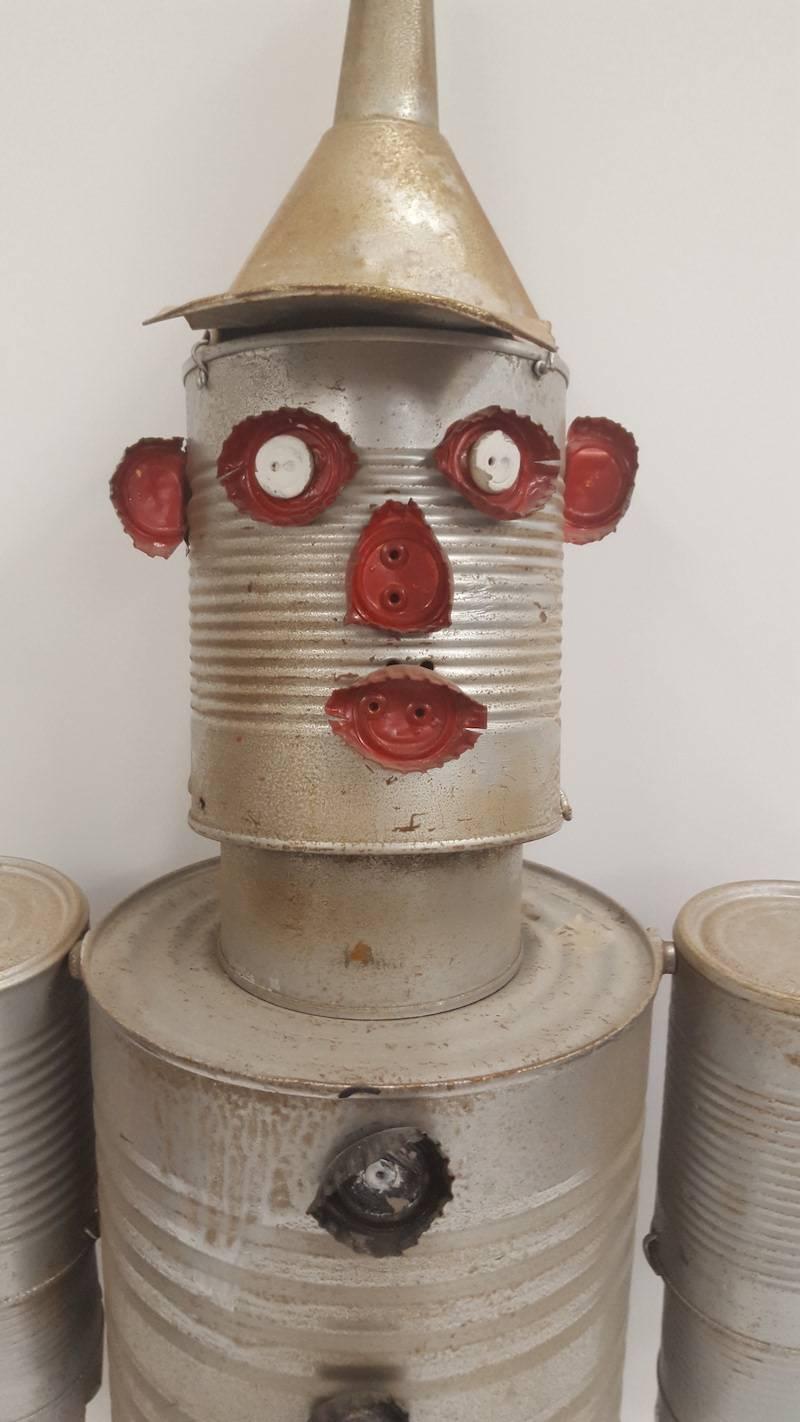 A sculptural figure made from tin cans, bottle tops, paint, wire, and rivets. It has moveable joints due to
the cans being connected with wire and some rivets. It is a charming collectable, which could be used as a decorative wall hanging. It was