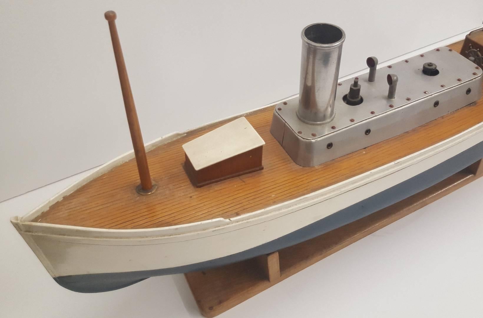 Painted model pond boat powered by a steam engine. Owned by current collector over 25 years without ever sailing the model. Metal (perhaps aluminium) centre parts on upper deck, including smoke stack, hand wheel, rudder, and air vents. Beautiful