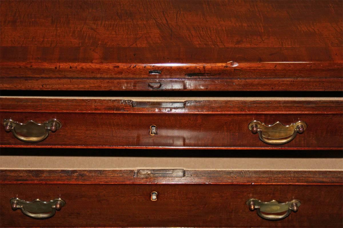 An 18th century English Georgian mahogany bachelor's Chest, the fold over rectangular top opens to a clothes folding tray above four lined drawers of graduating size, the drawer bottom in oak and running front to back, the sides each fitted with